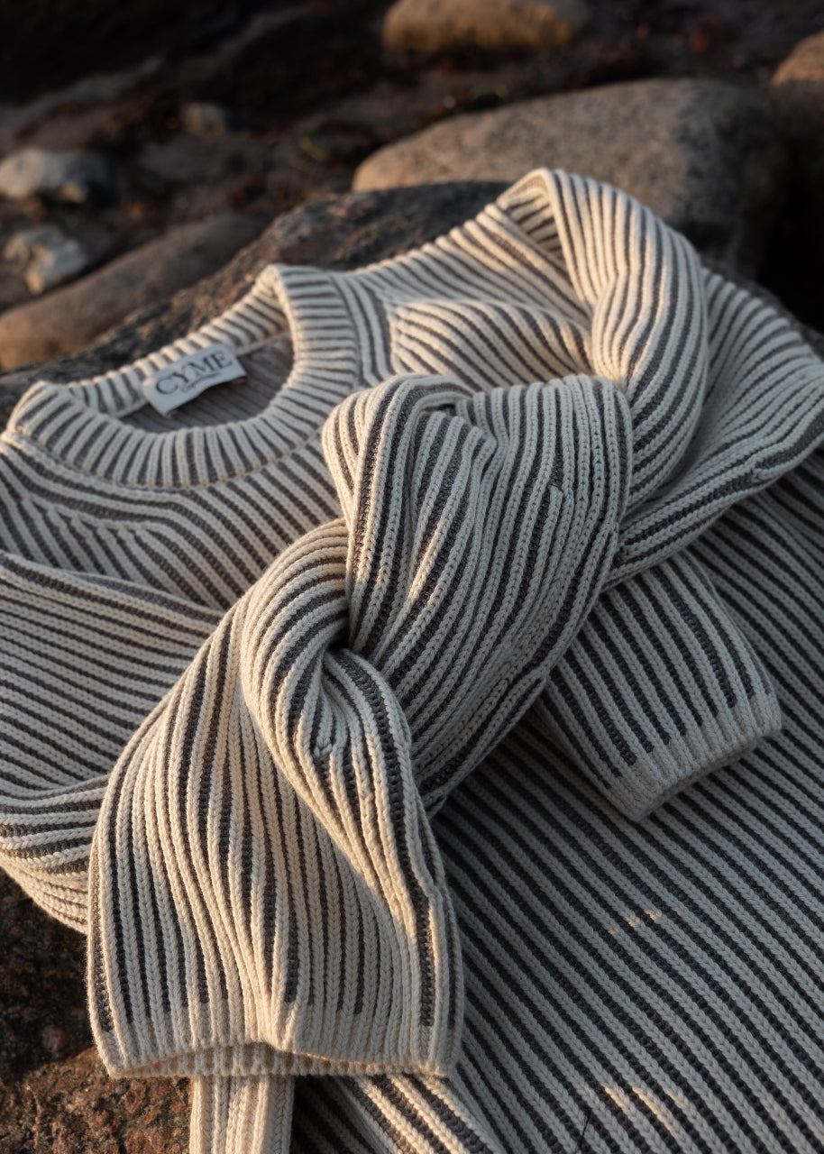 Striped cotton cashmere jumper worn in a natural forest setting, embodying CYME Copenhagen's slow fashion philosophy