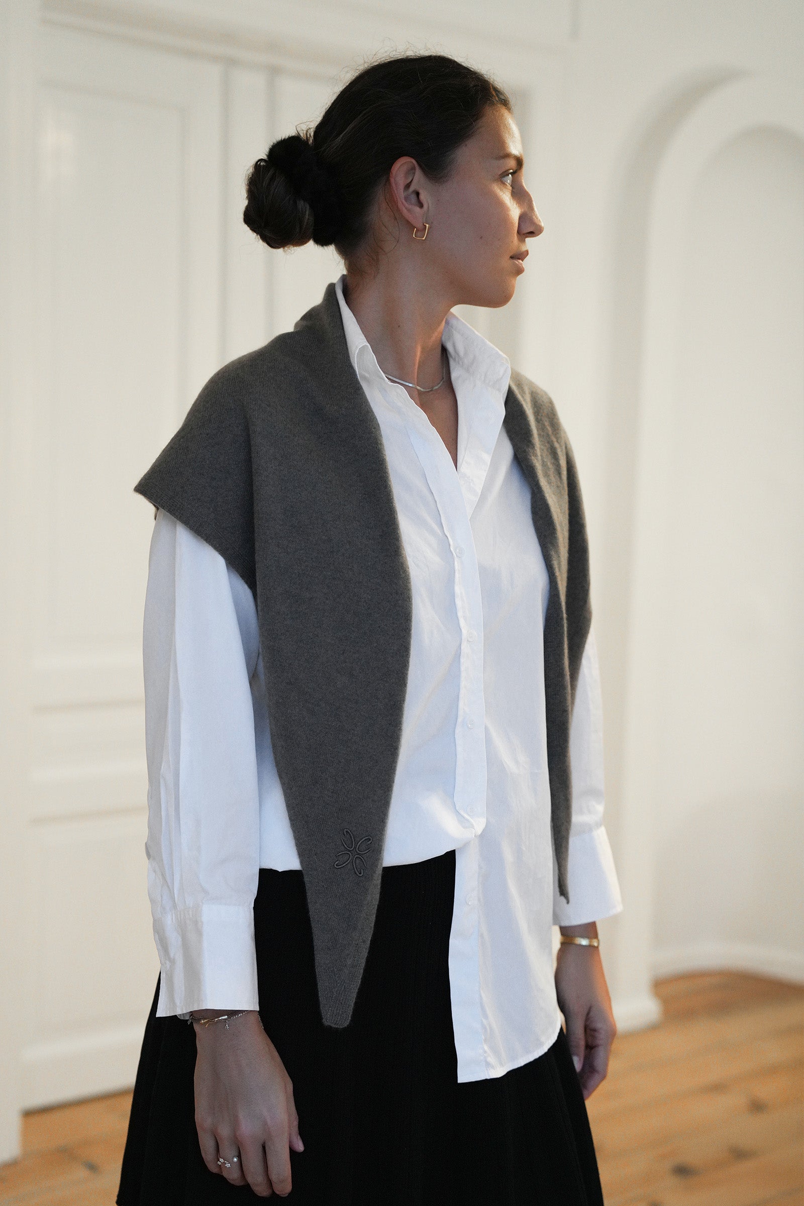 Woman wearing a white shirt and dark vest in a minimalistic setting