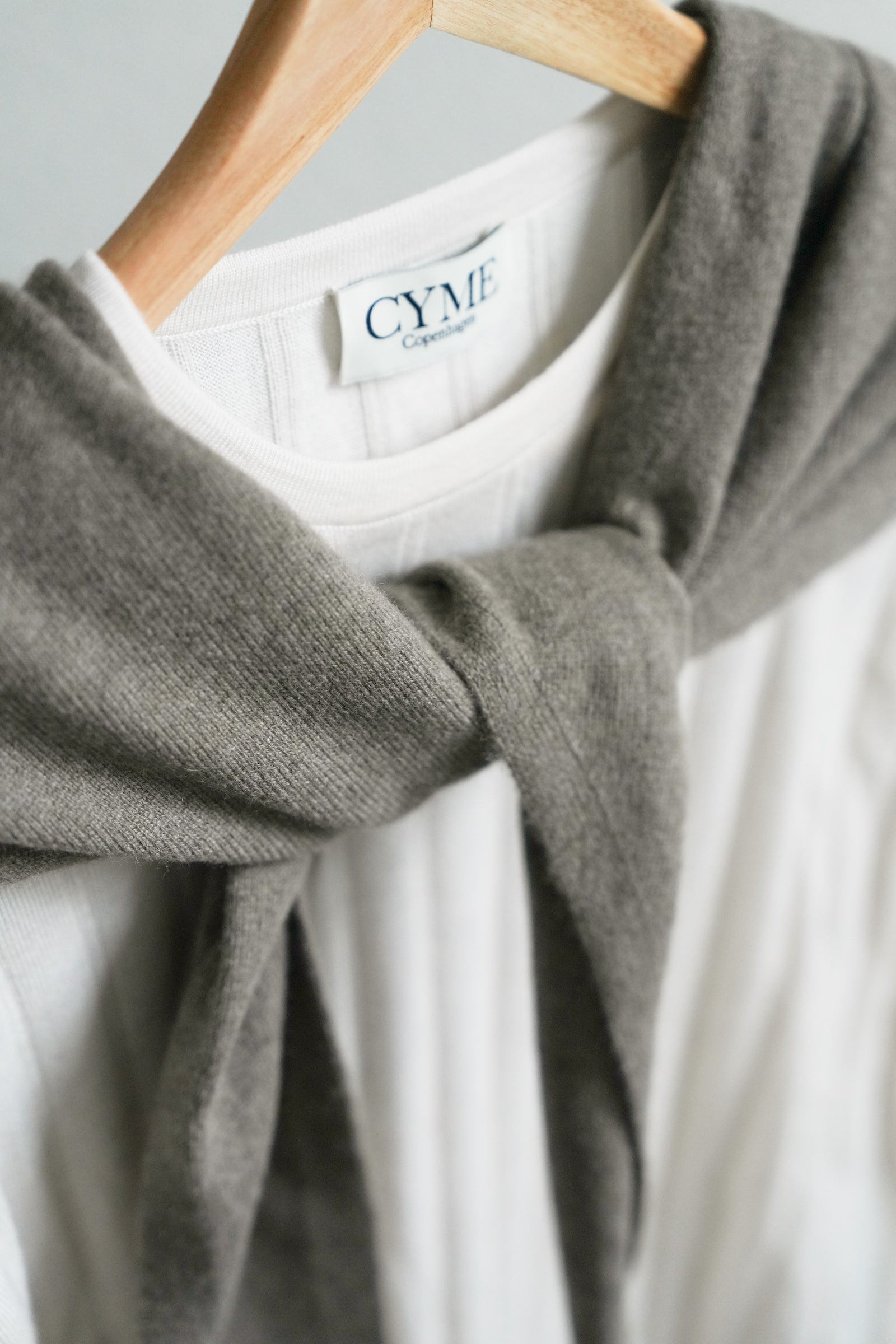 Gray sweater on a hanger with a visible brand label against a neutral background