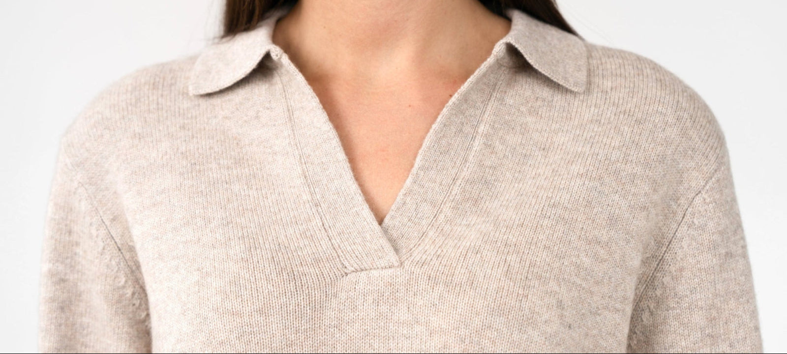 A close up picture of a dark haired woman wearing a cashmere polo jumper.