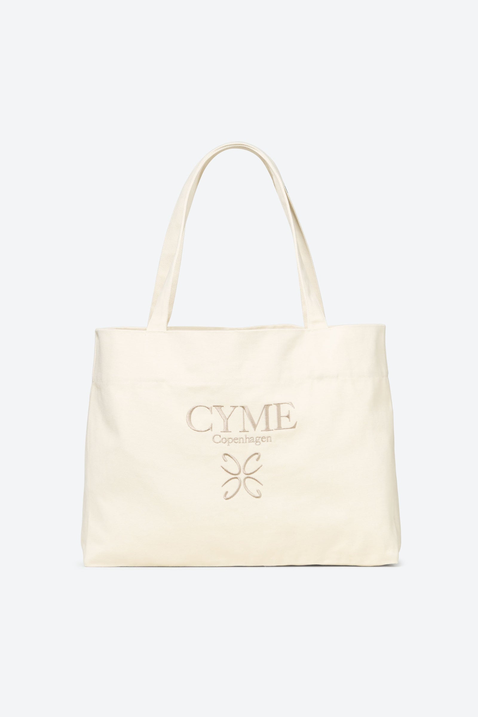 A cream-colored tote bag with "CYME Copenhagen" embroidered in beige thread on the front. The bag features a structured design with sturdy handles, making it a versatile and elegant choice for everyday use.