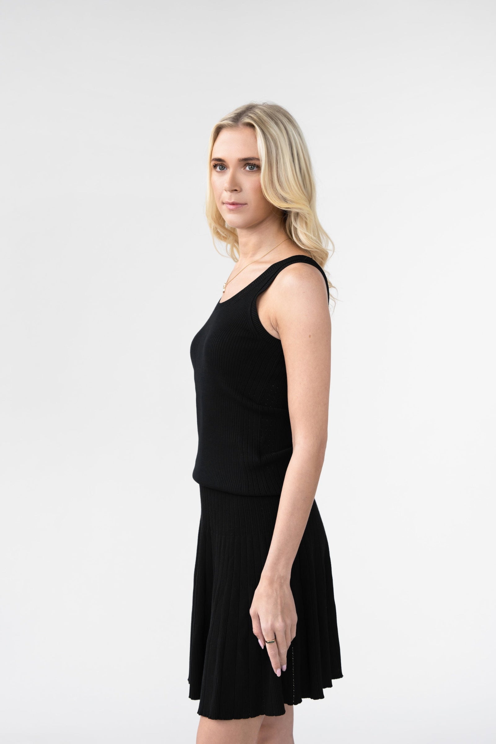 Woman wearing a black sleeveless top and skirt against a white background
