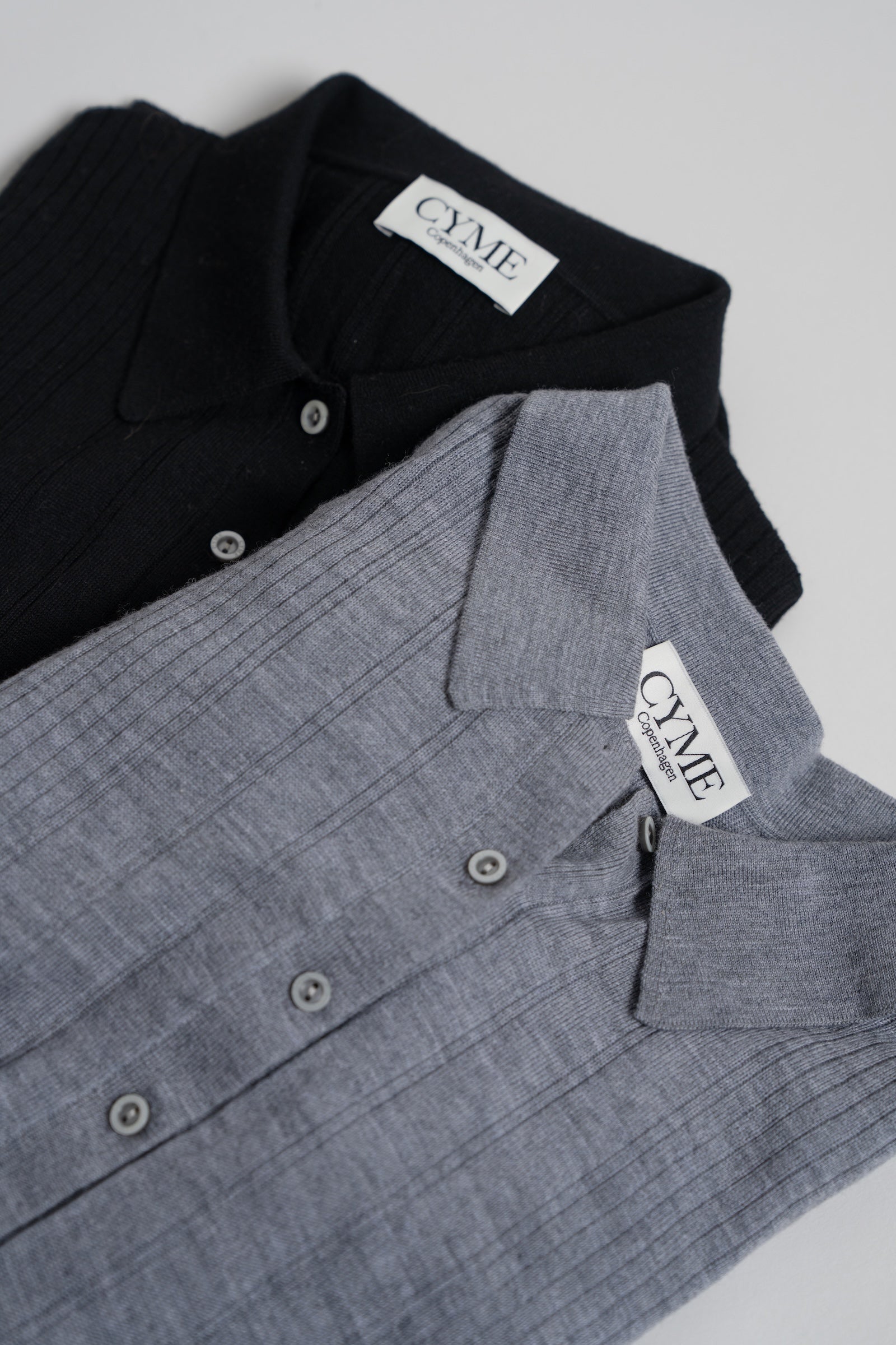 Black and gray shirts with 'CYME' labels on a white background