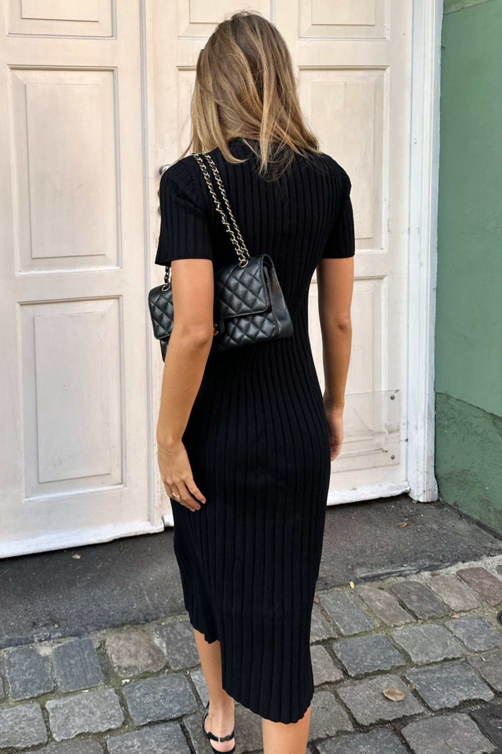 Model displaying Cyme Copenhagen's sustainable fashion line, a sleek black ribbed knit dress, embodying the elegant simplicity of Danish design available in inclusive sizes.
