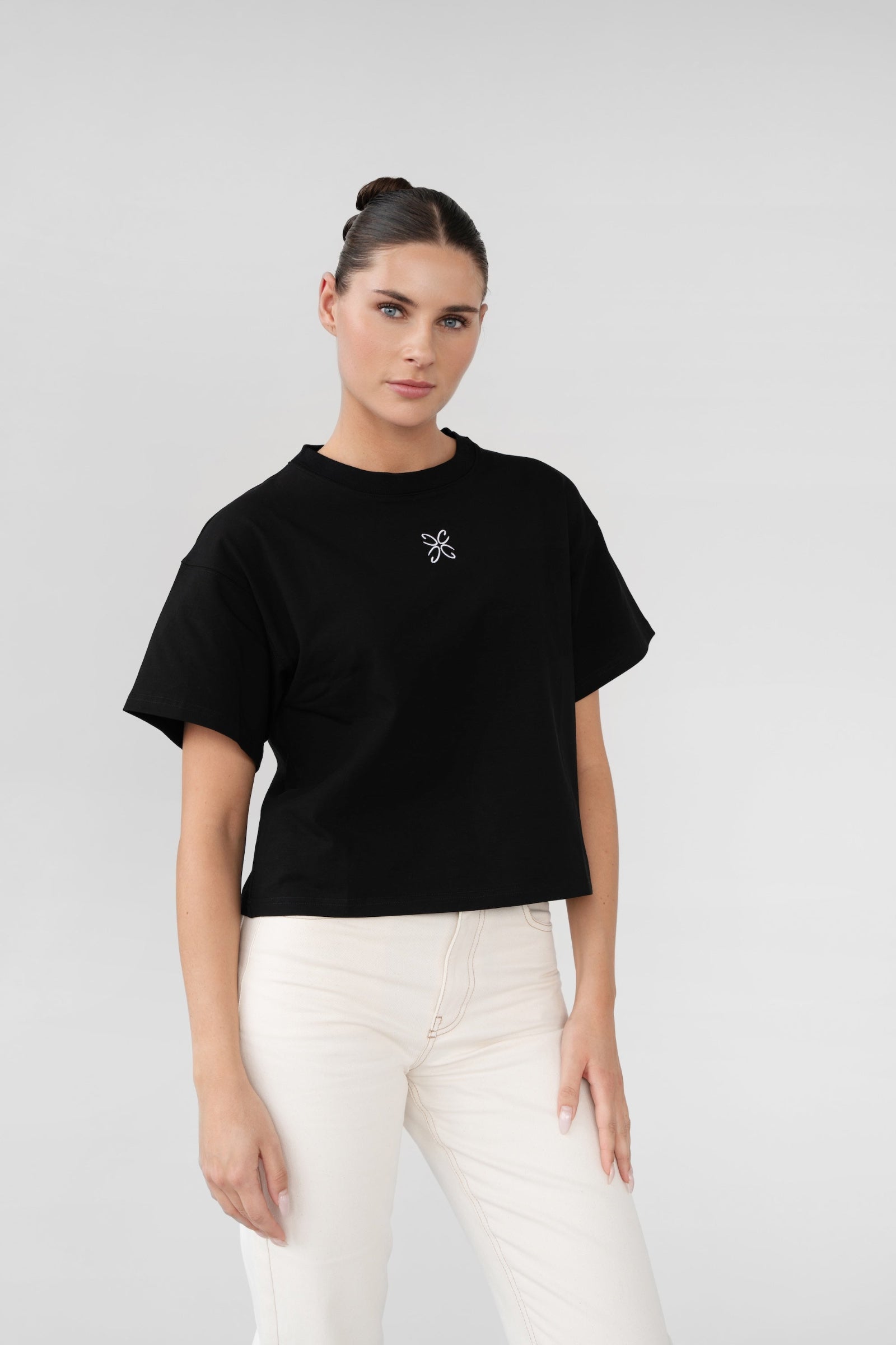 Woman wearing a black t-shirt with a white logo on a plain background