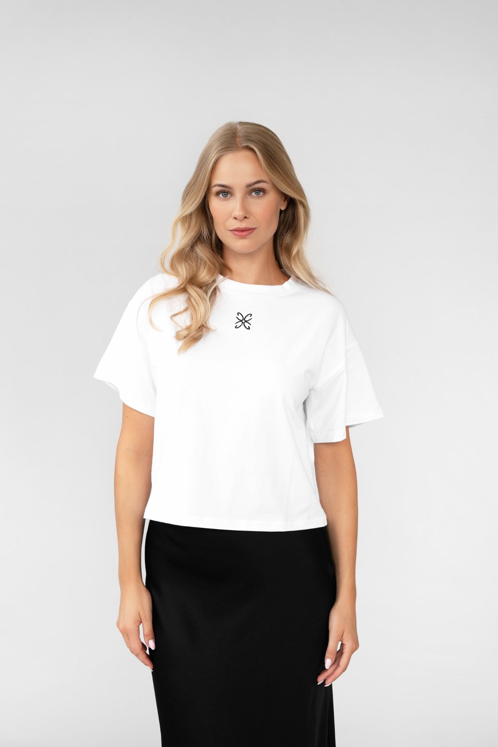 Woman wearing a white blouse with a black skirt on a light gray background