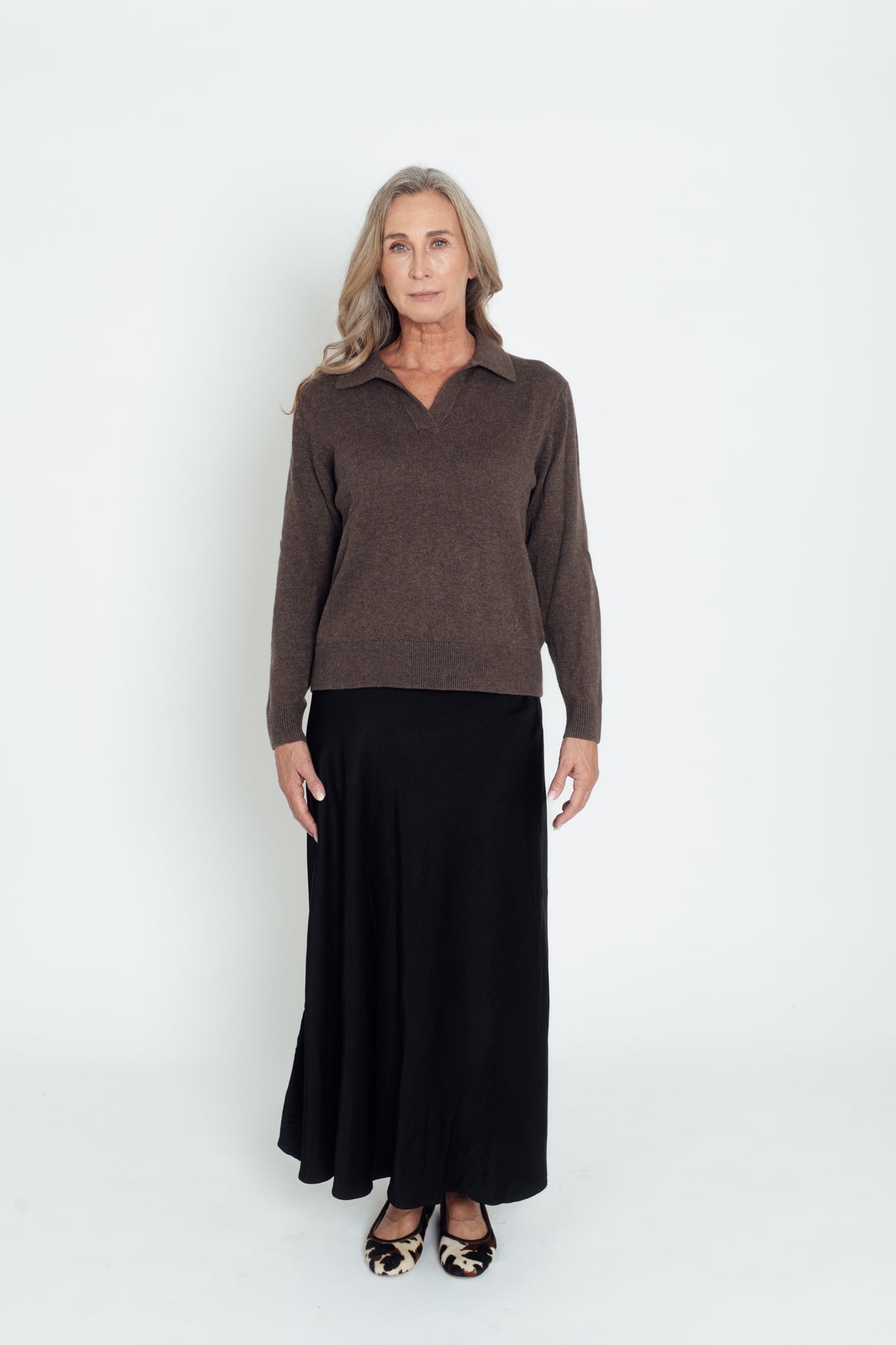 Full-length front view of the dark brown Cashmere-Merino Polo Jumper with a black skirt.