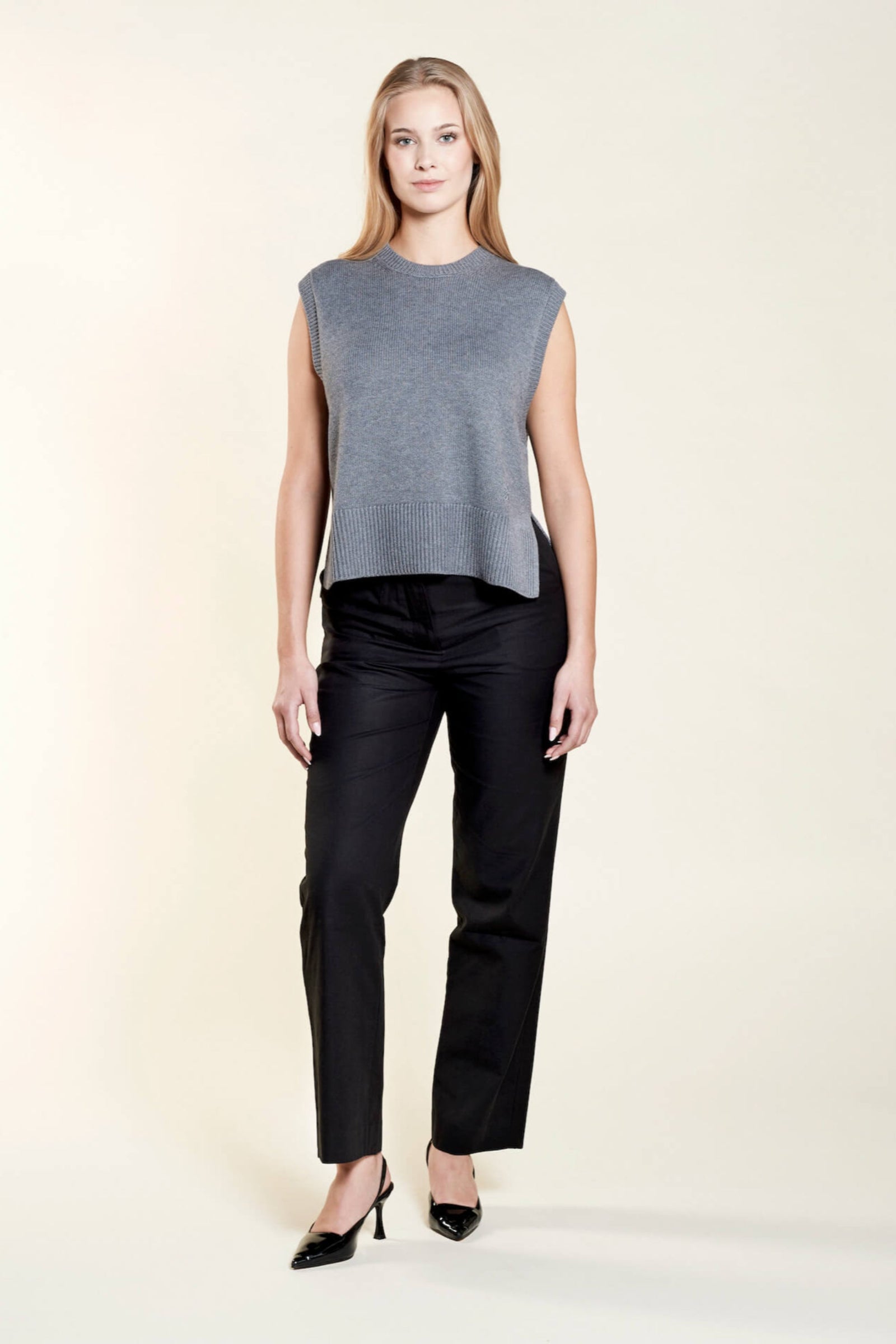 A model confidently wears a Cyme Copenhagen classic black trousers with a chic black cropped top composed with lyocell, highlighting the brand's flair for combining sustainable fashion with timeless Scandinavian design.