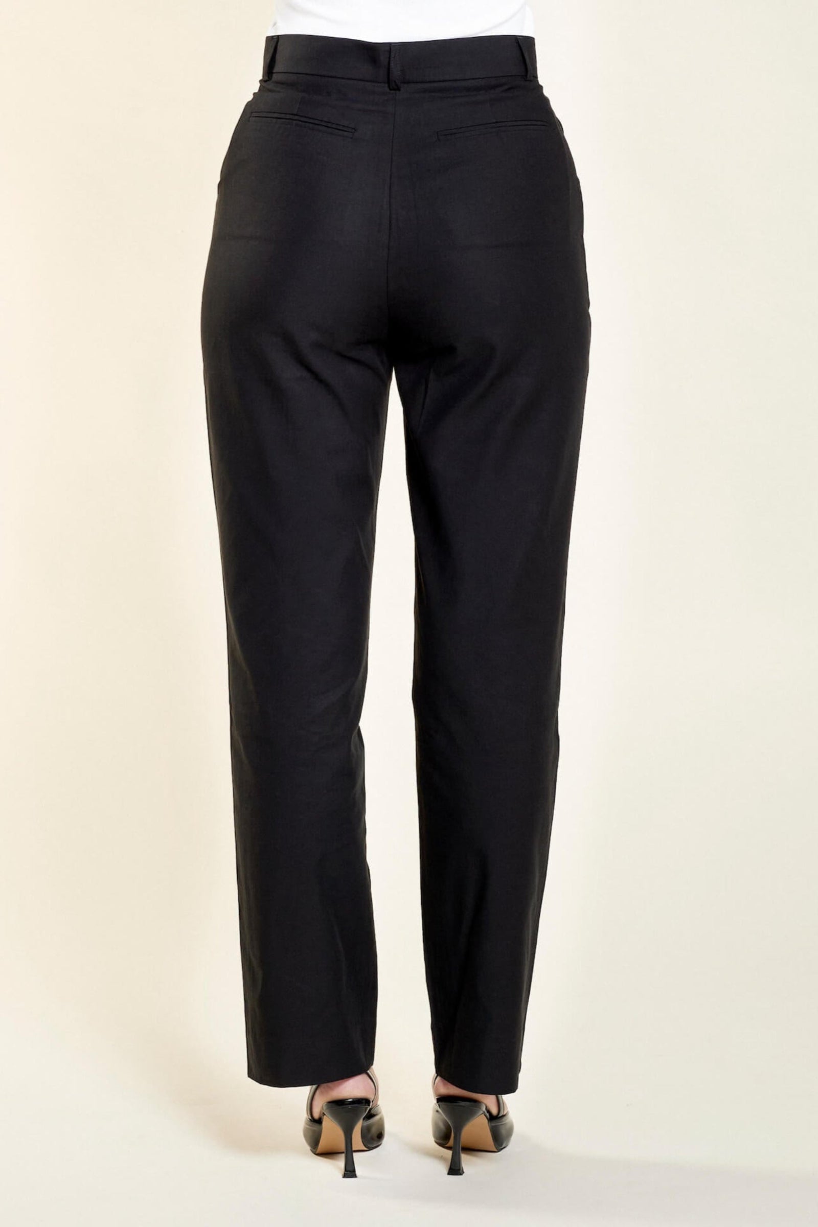 Side view of a model in Cyme Copenhagen's tailored black lyocell trousers highlighting a nice fit with a sleek design, embodying the essence of sustainable and timeless Scandinavian fashion.