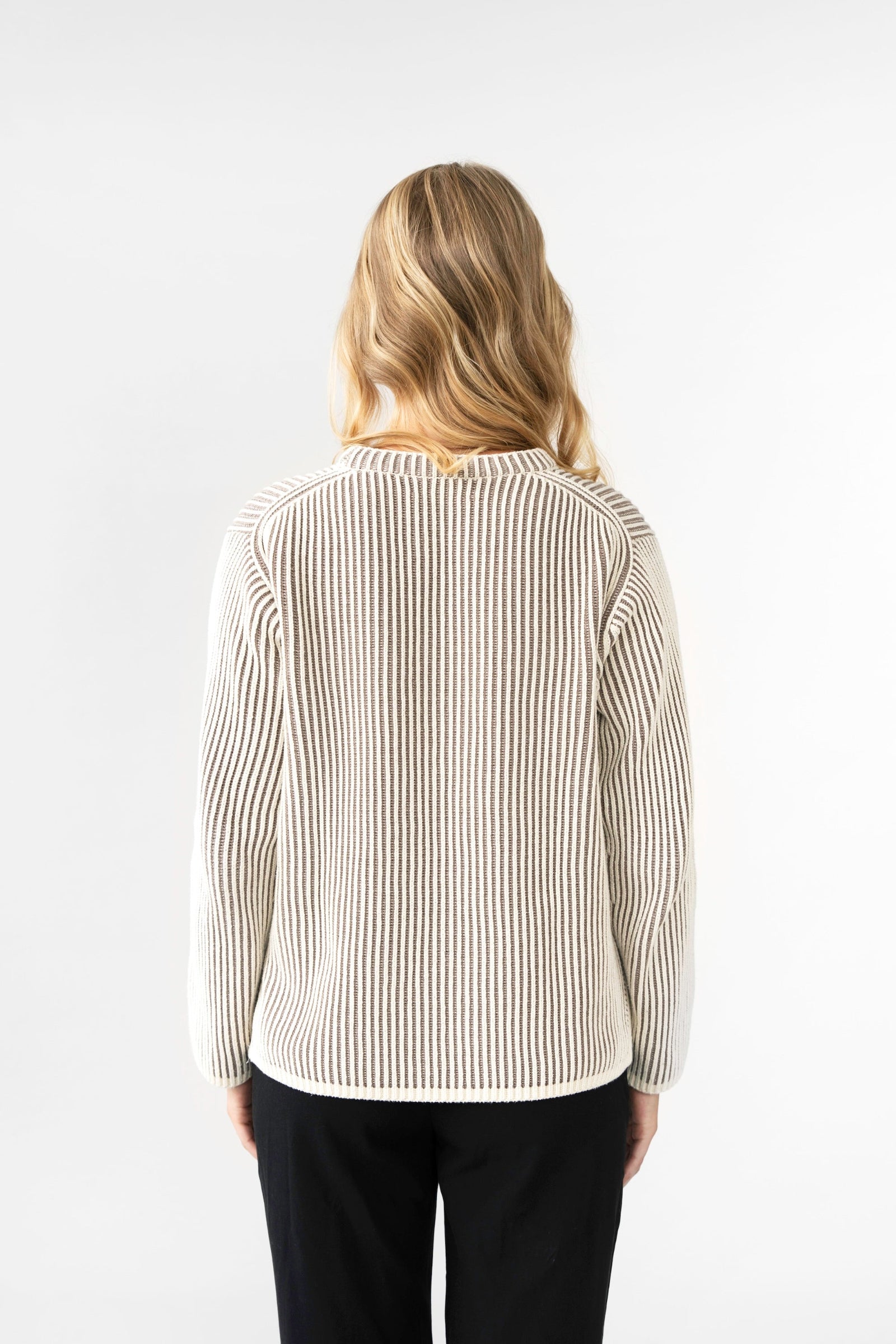 Person wearing a striped shirt and black pants on a white background