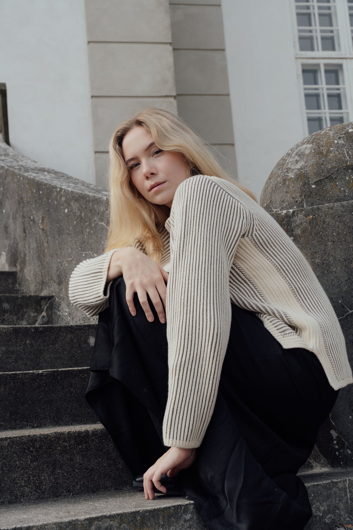 Cream/Fur Cotton Cashmere Jumper worn on a seated model, showing its long striped sleeves.