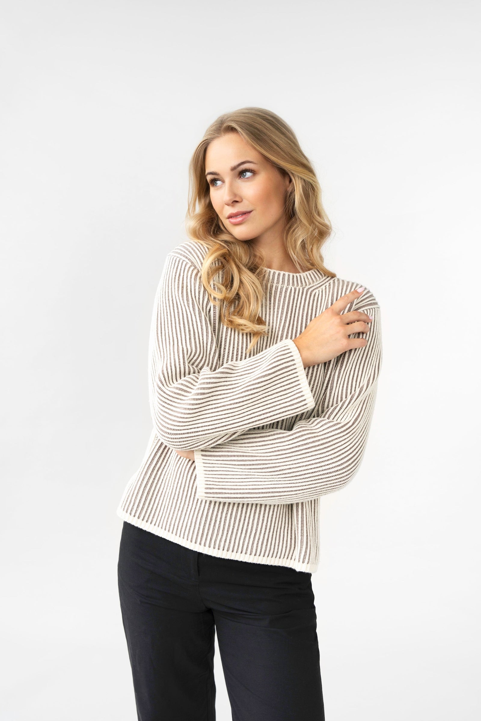Woman wearing a striped sweater and black pants on a white background