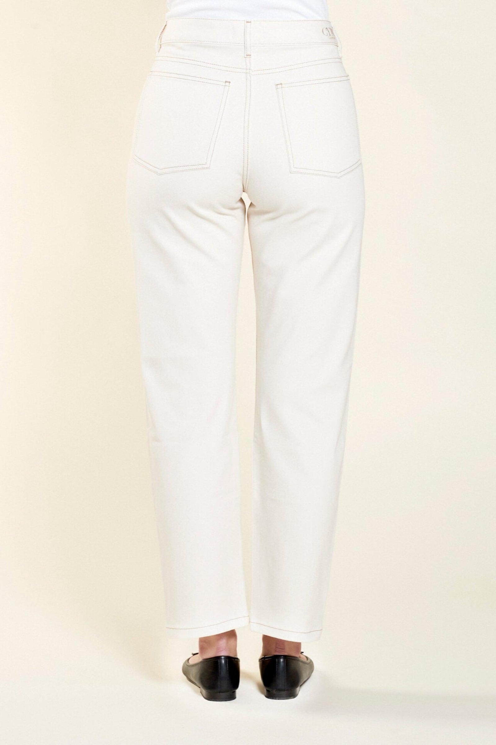 Rear view of Cyme Copenhagen's cream denim trousers, featuring a clean and classic design with signature branding on the waistband, showcasing the sustainable and chic Danish fashion ethos.