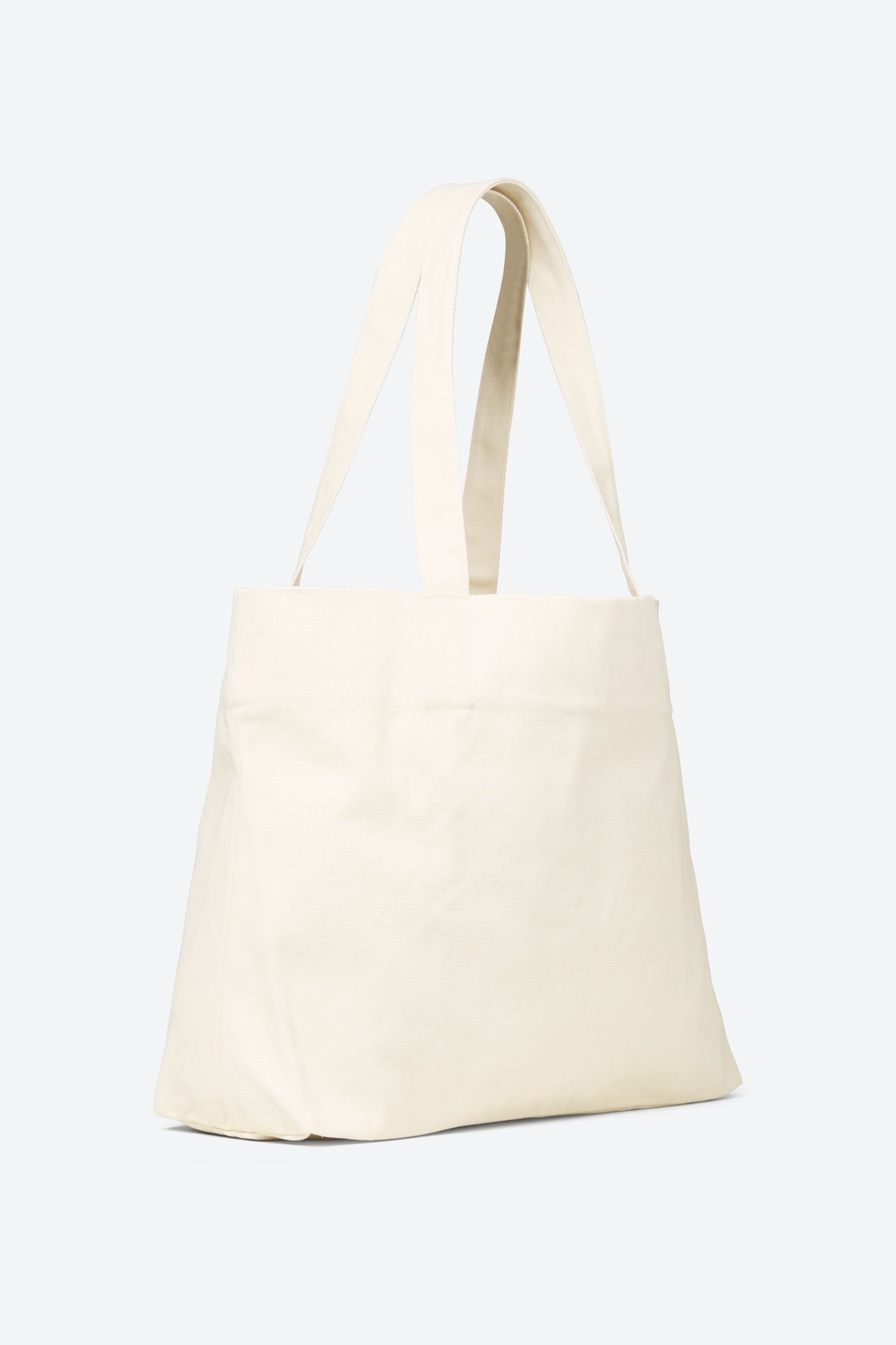 Side view of the cream-colored CYME Copenhagen tote bag, showcasing its deep storage capacity and soft yet durable fabric.