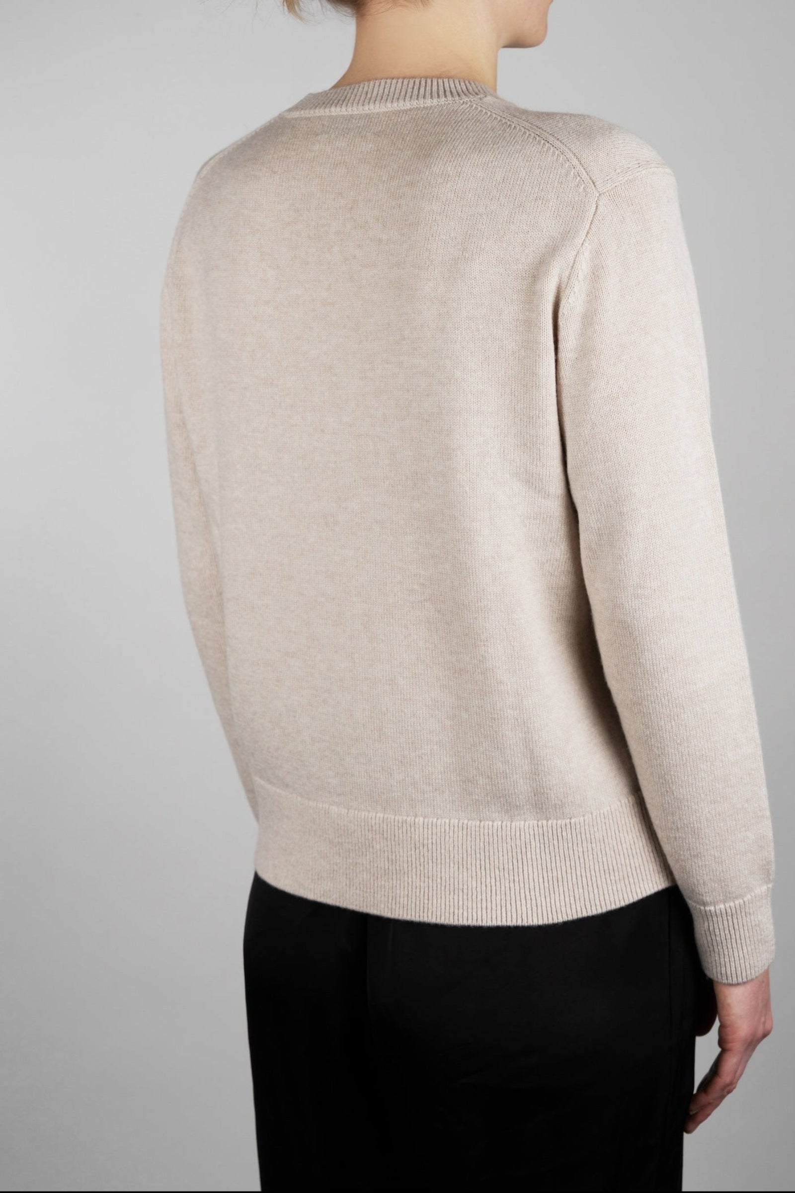 Beige sweater worn by a person on a plain background