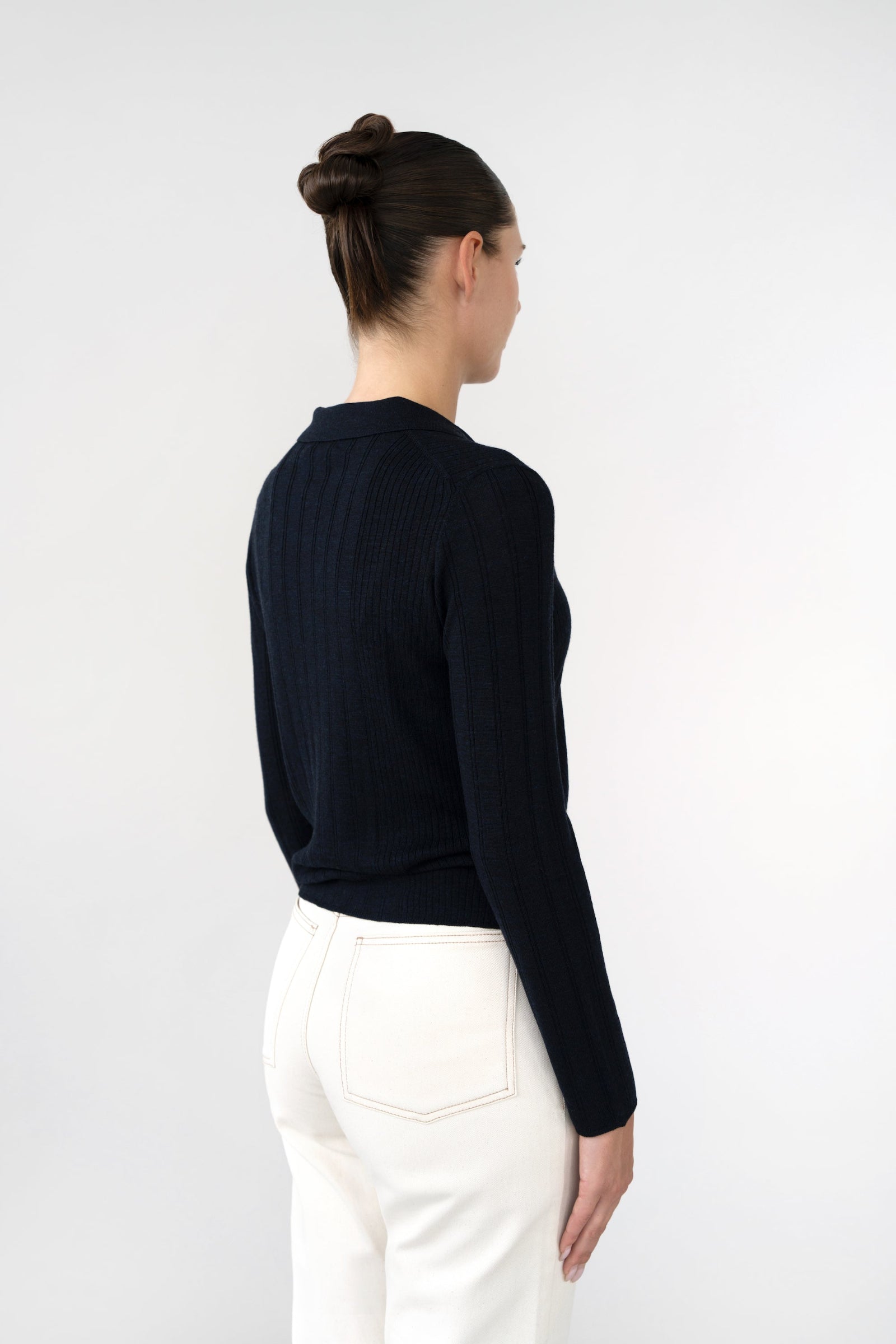 On-model back view of ribbed knit collared cardigan, navy, rib texture, studio.