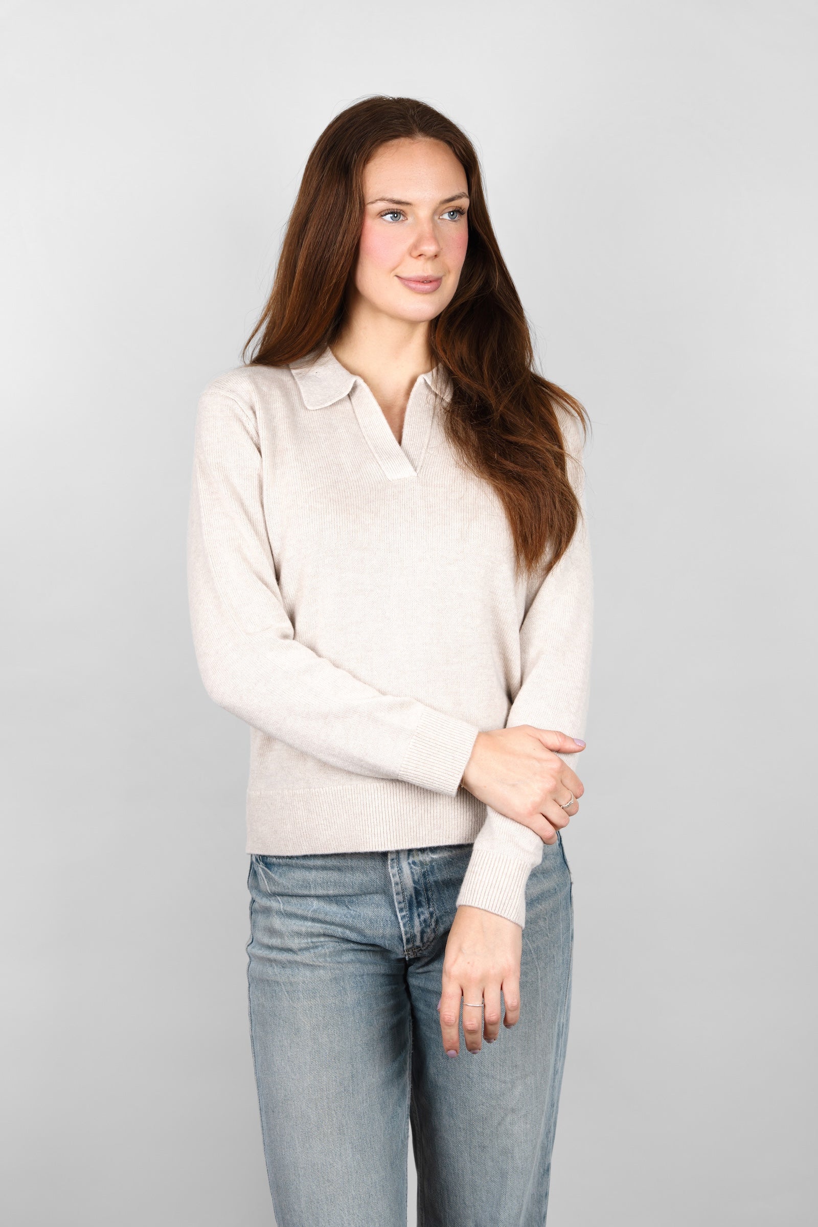 Front view of the CYME Cashmere-Merino Polo Jumper in beige, worn on-model with jeans. This relaxed polo jumper has an open collar and is knitted in a soft cashmere-merino blend.