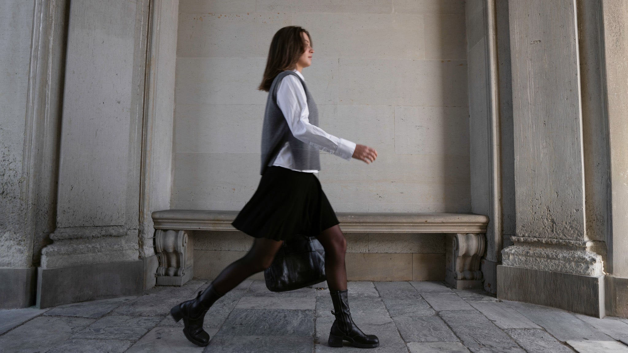 Person walking in a classical architectural setting wearing CYME Copenhagen styles.
