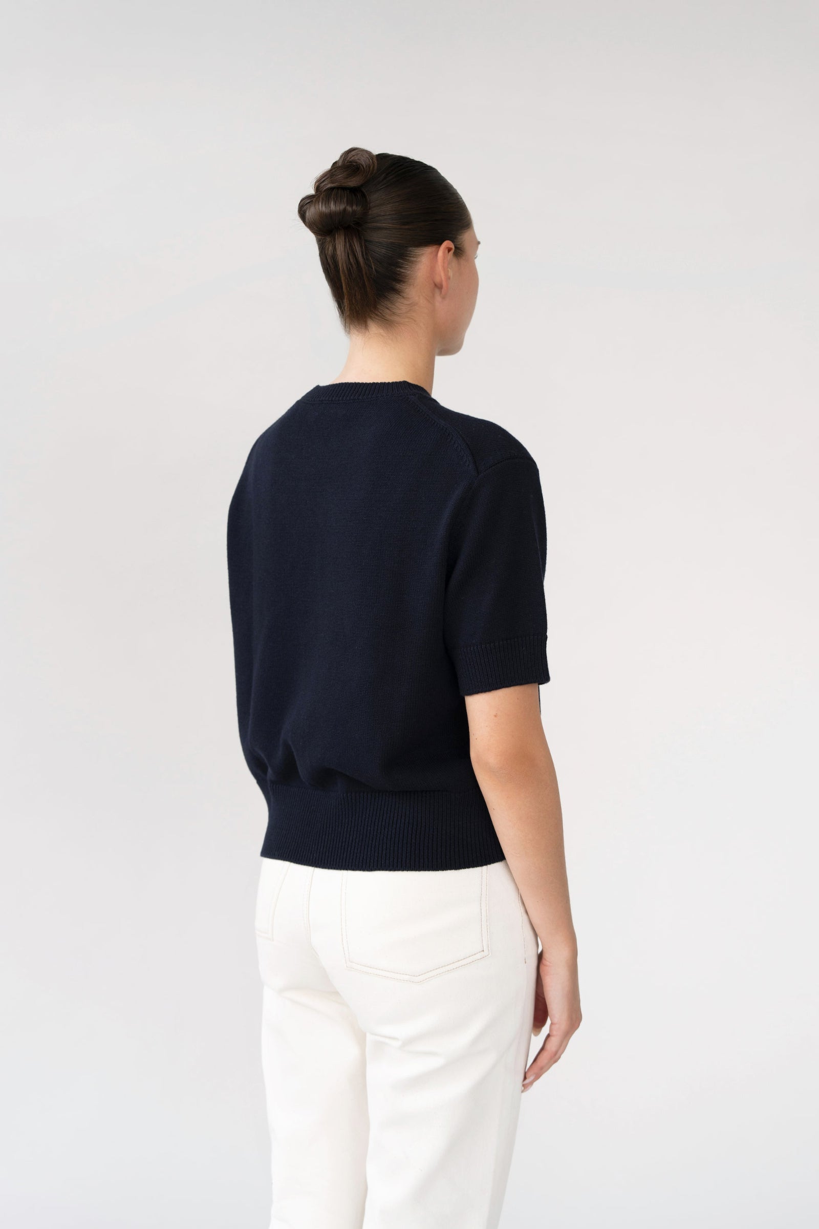 On-model back view of short-sleeve knit top, navy, ribbed trims, studio.