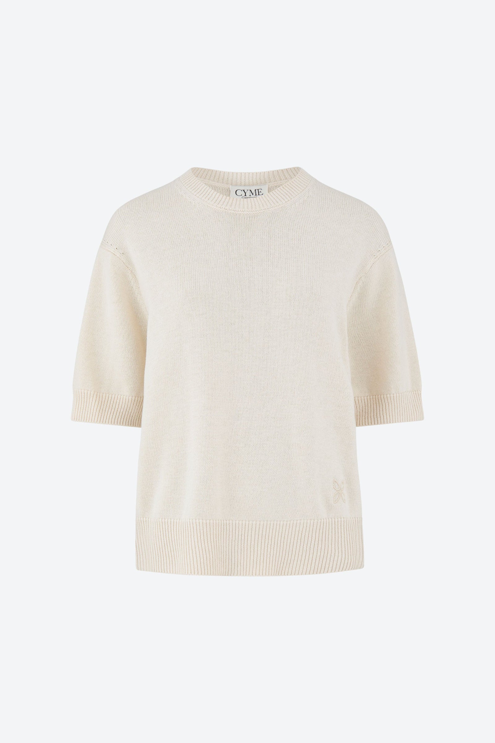 Front view of an off-white, short-sleeve sweater with a crew neckline. The sweater has a ribbed hem and cuffs, featuring a subtle embroidered logo near the bottom edge. The sweater is displayed on a plain background.