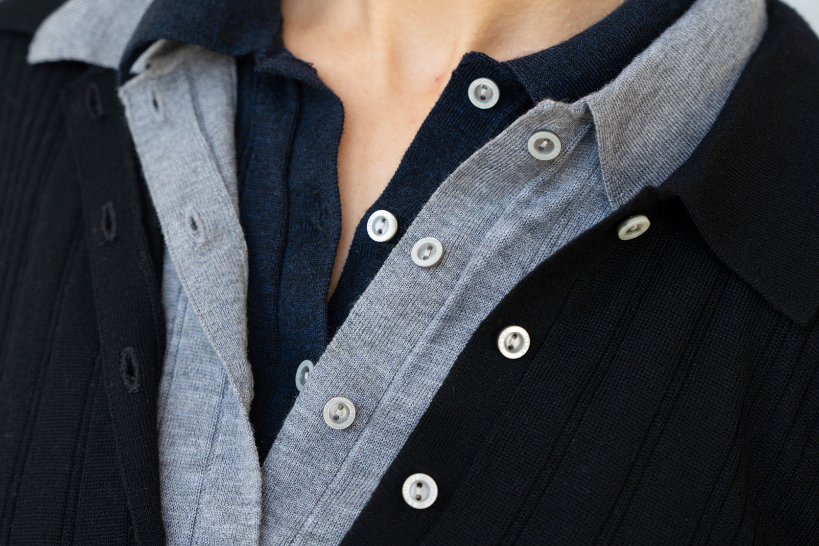 Close-up of a person wearing a dark jacket with a gray shirt underneath.