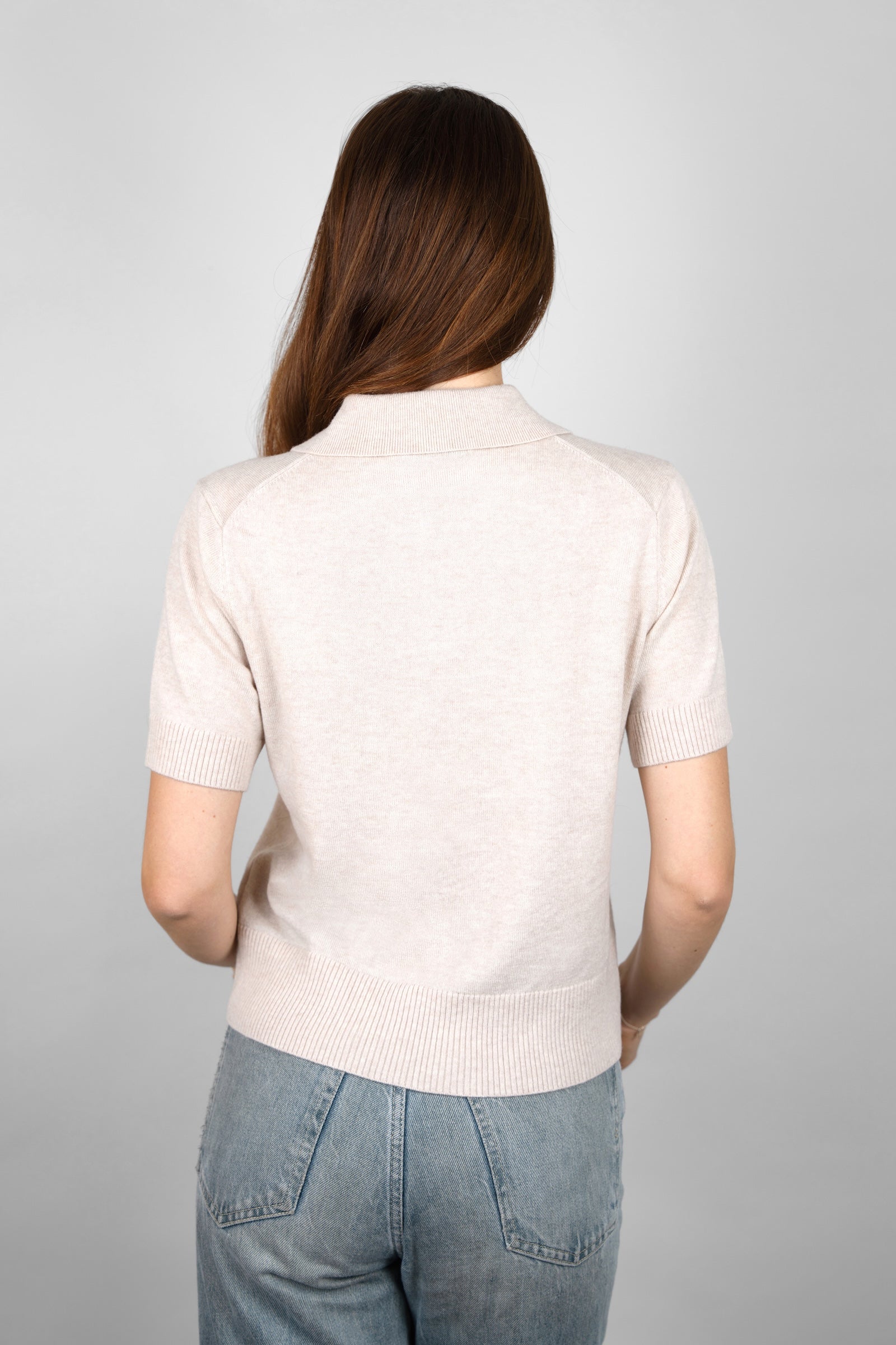 Back view of the CYME Short Sleeve Polo Shirt in beige, highlighting the neat collar and ribbed cuffs and hem. Made in a soft knit for relaxed, everyday styling.