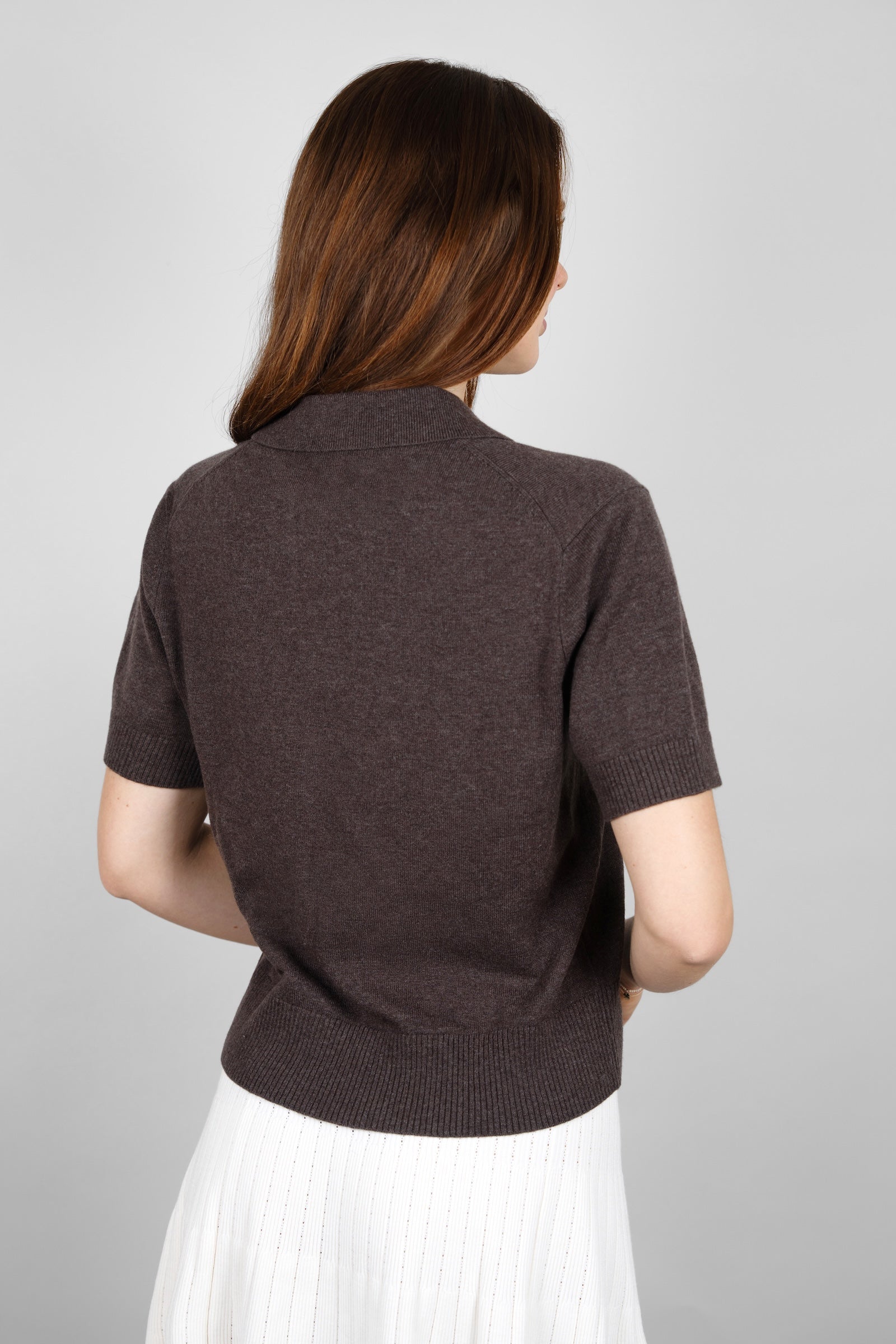 Angled back view of the CYME Short Sleeve Polo Shirt in dark brown, highlighting the soft knit and neat collar. Its short-sleeve silhouette layers easily for everyday wear.