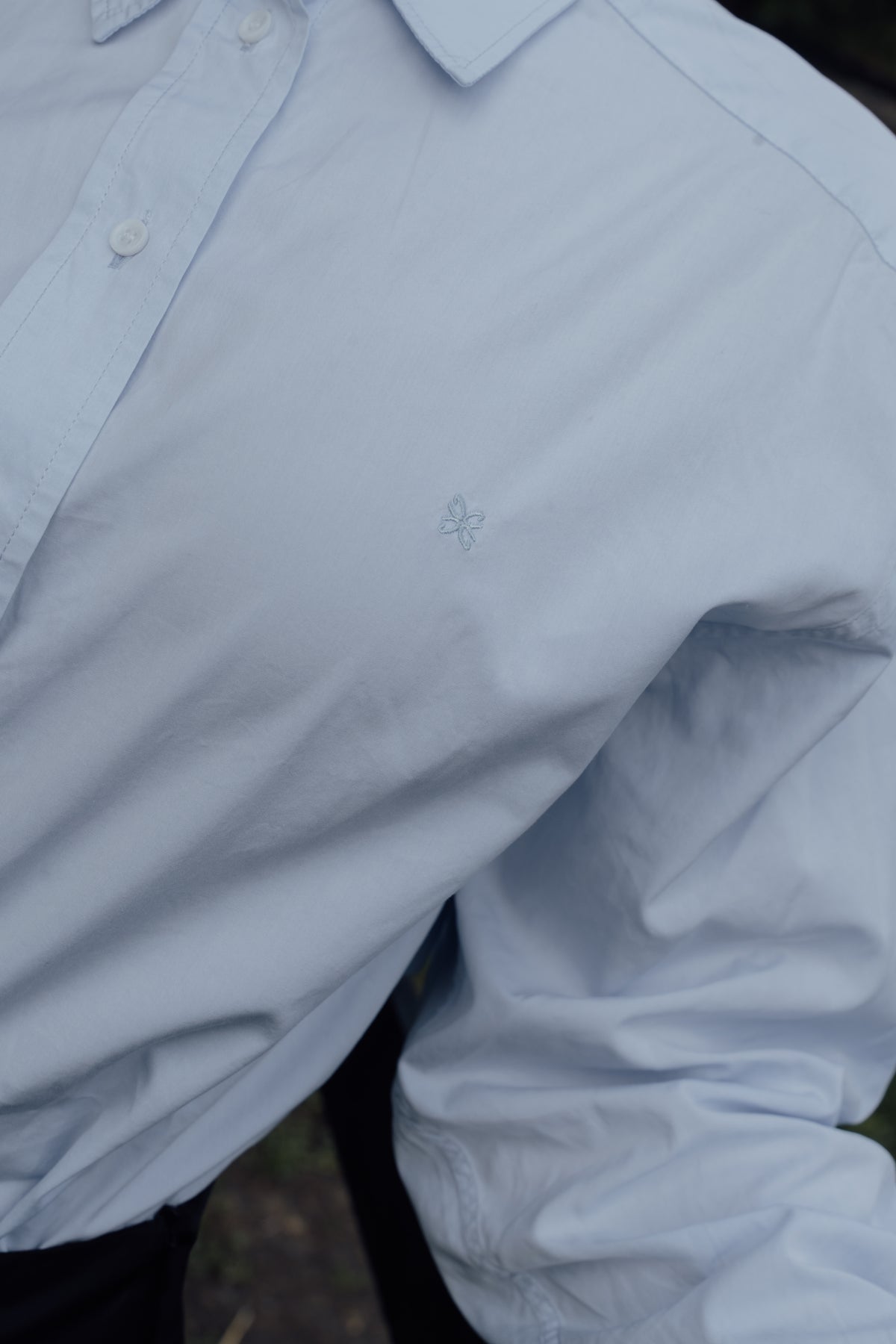 Close-up of the light blue Cyme Supima Shirt's button front and embroidered CYME logo.