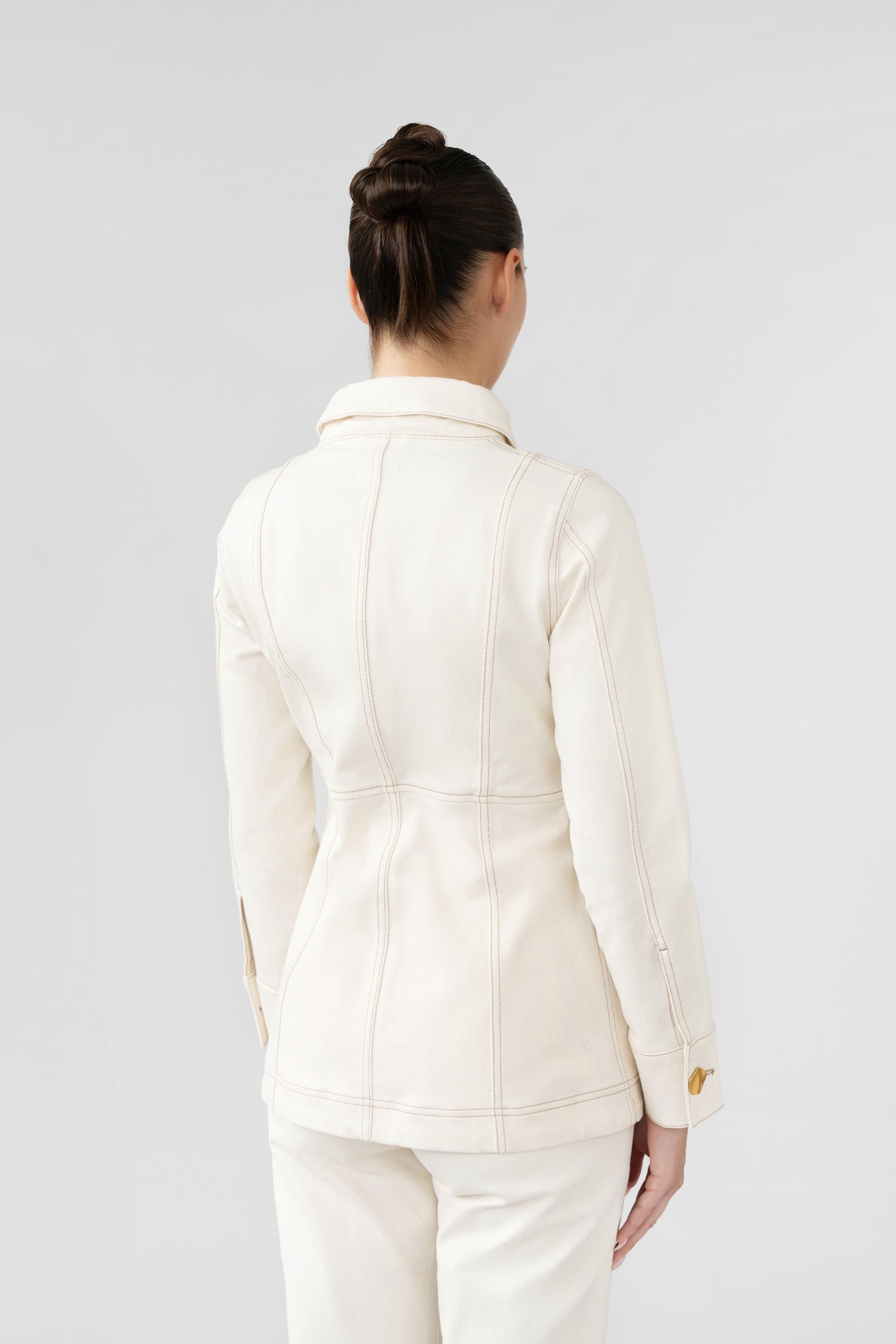 Person wearing a white blazer and pants on a light gray background