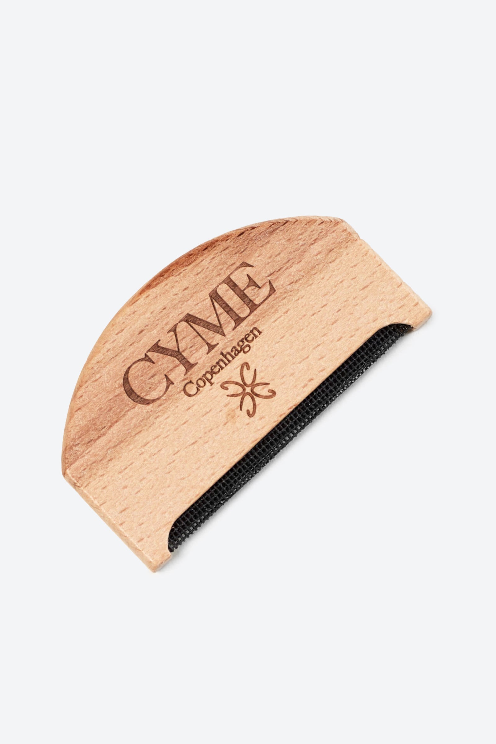 Close-up of a wooden garment comb from CYME Copenhagen. The comb features the CYME Copenhagen logo and branding engraved on the wood, with a fine black mesh edge for removing lint and pilling from clothing.