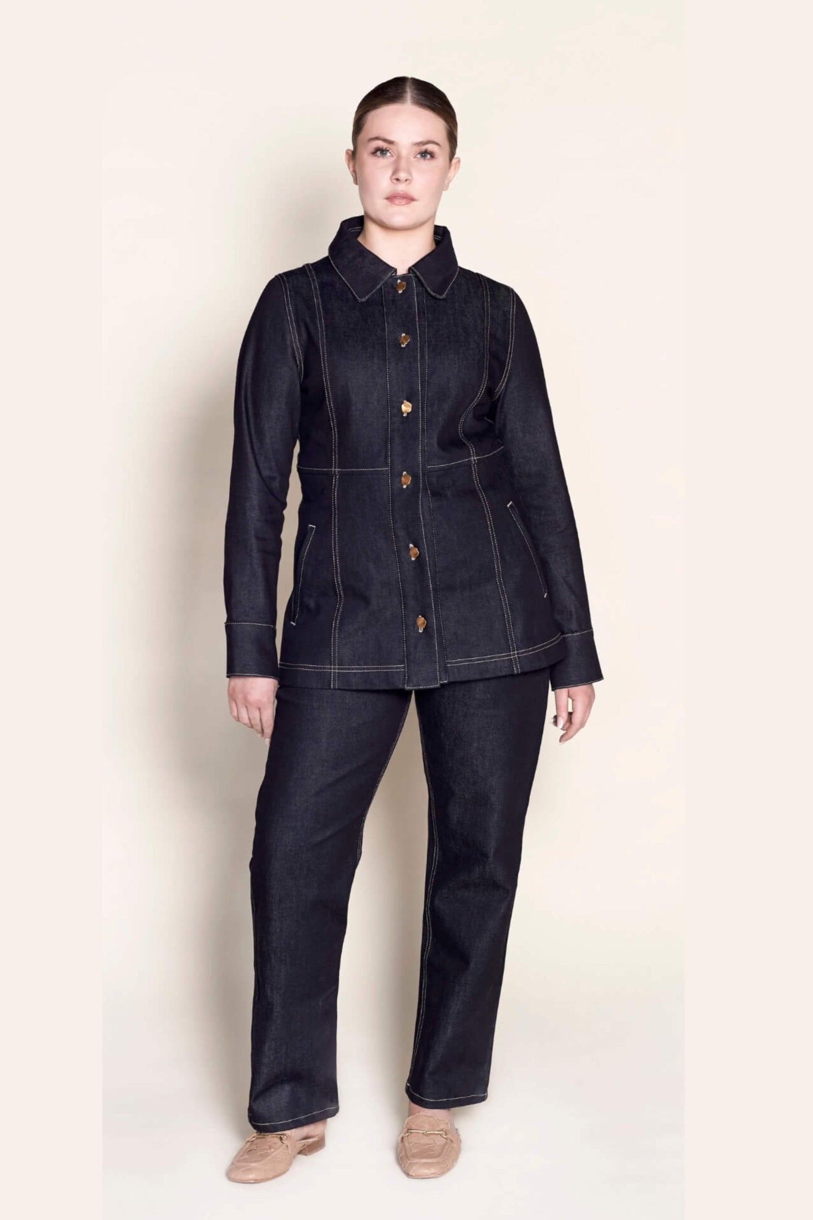 Model in a full Cyme Copenhagen outfit featuring a tailored dark denim jacket with wooden button details and matching jeans, reflecting the Danish designer's commitment to sustainable and timeless fashion.