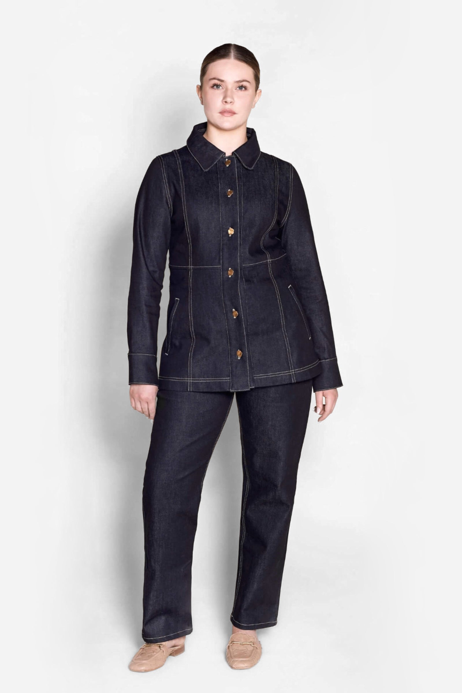 Model in a full Cyme Copenhagen outfit featuring a tailored dark denim jacket with wooden button details and matching jeans, reflecting the Danish designer's commitment to sustainable and timeless fashion.