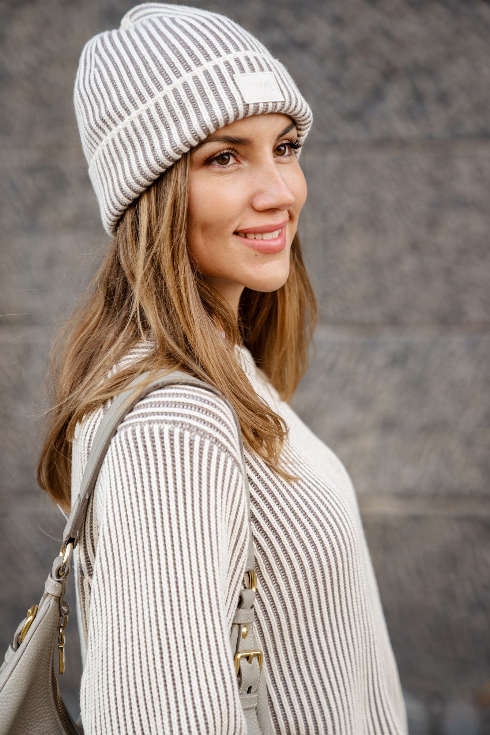 Woman wearing a striped beanie and sweater with a blurred background