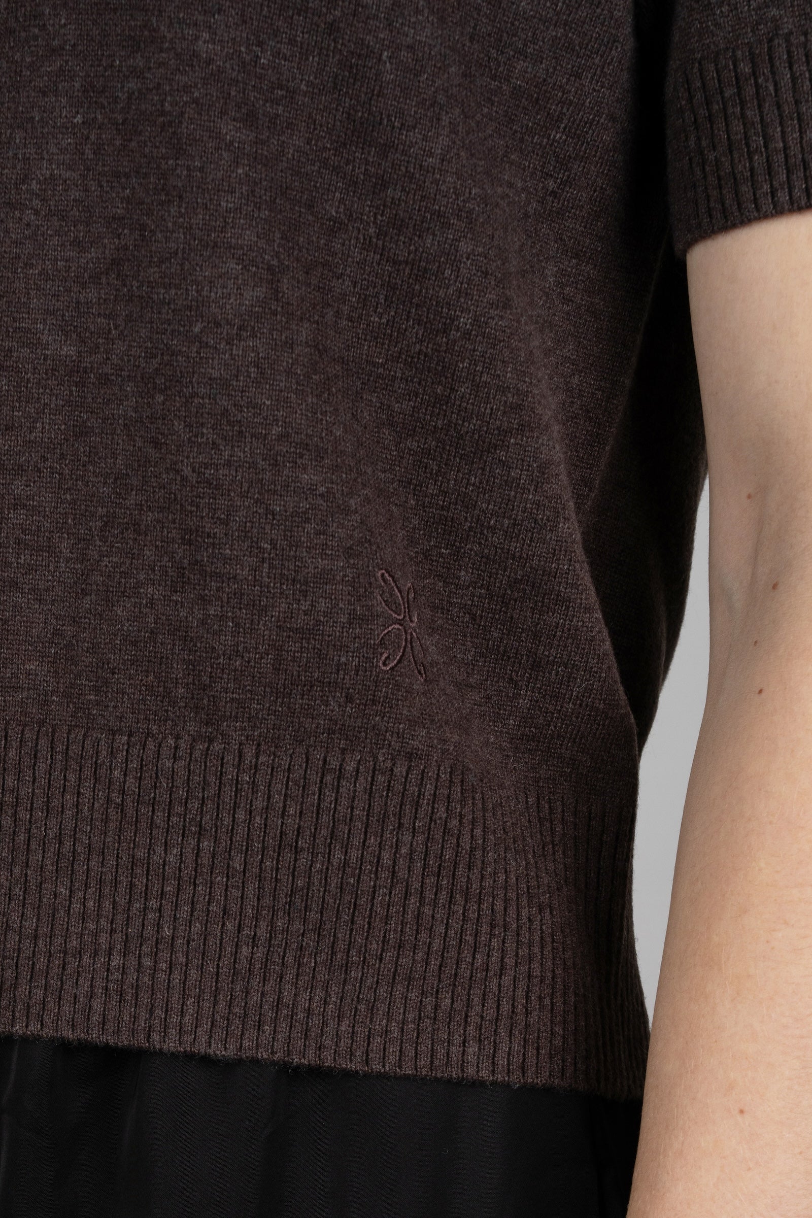 Close-up of a dark brown knitted sweater on a plain background