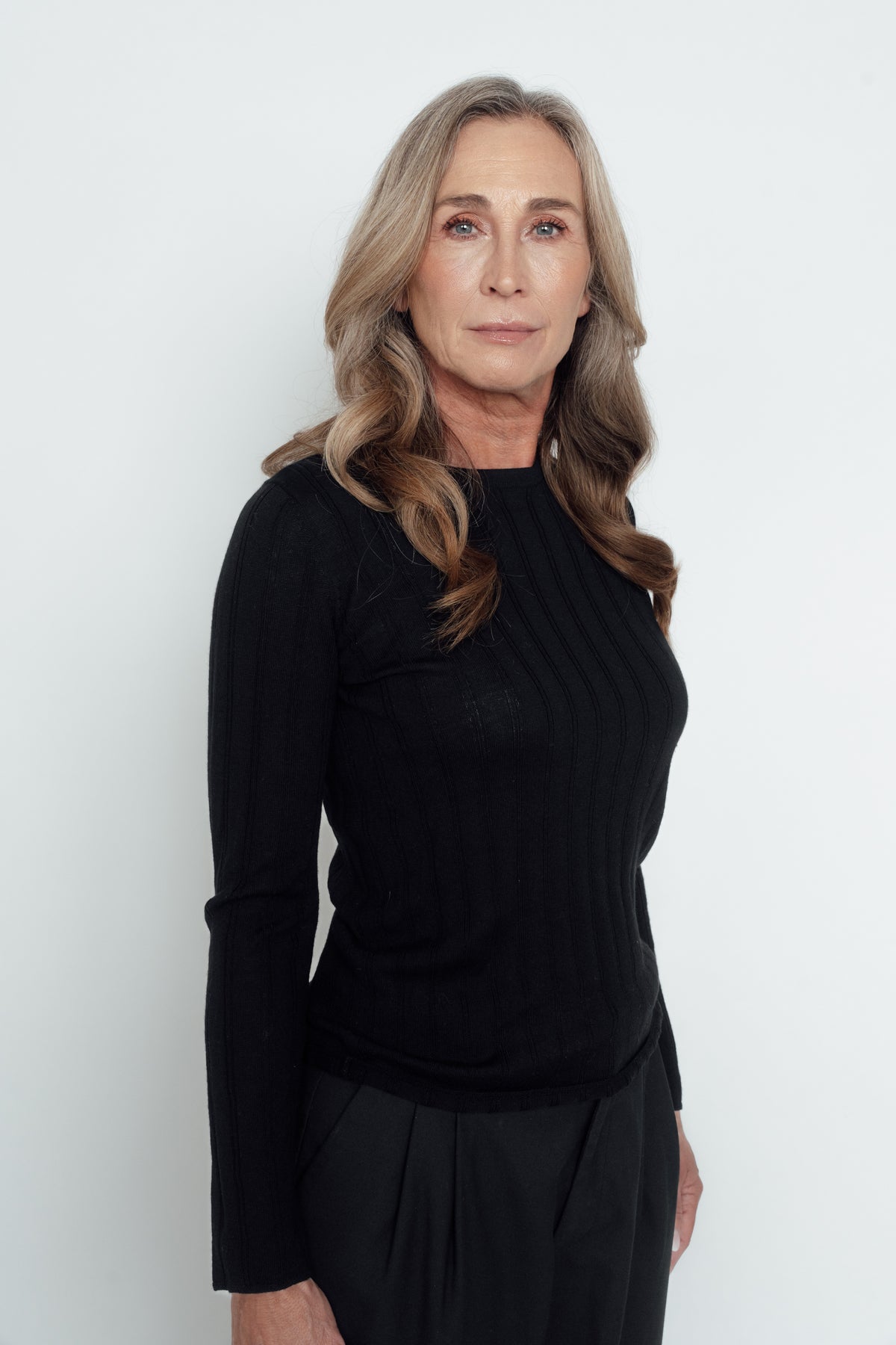 Angled front view of the black Ivy Merino Top, showing its vertical knit detailing and long sleeves.