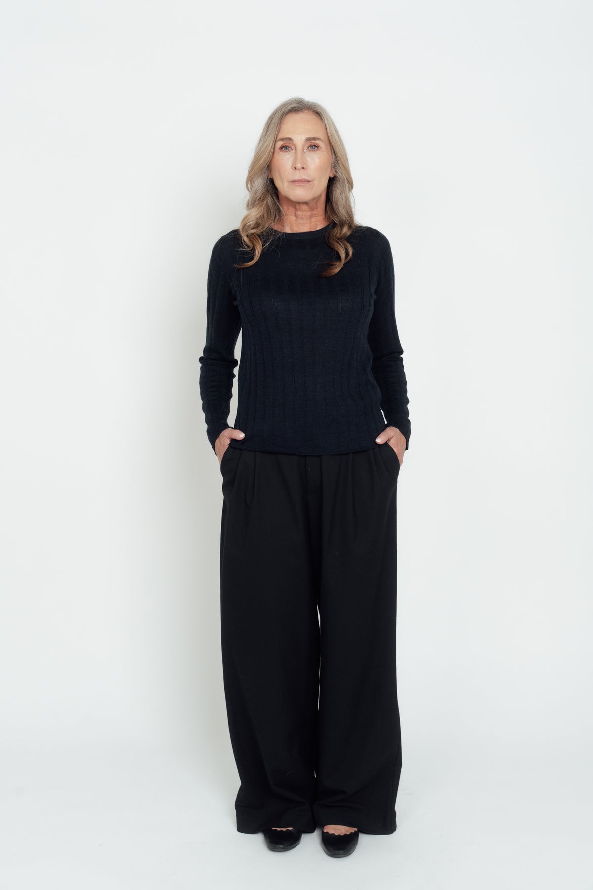 Front view of the navy Ivy Merino Top worn with black wide-leg trousers.