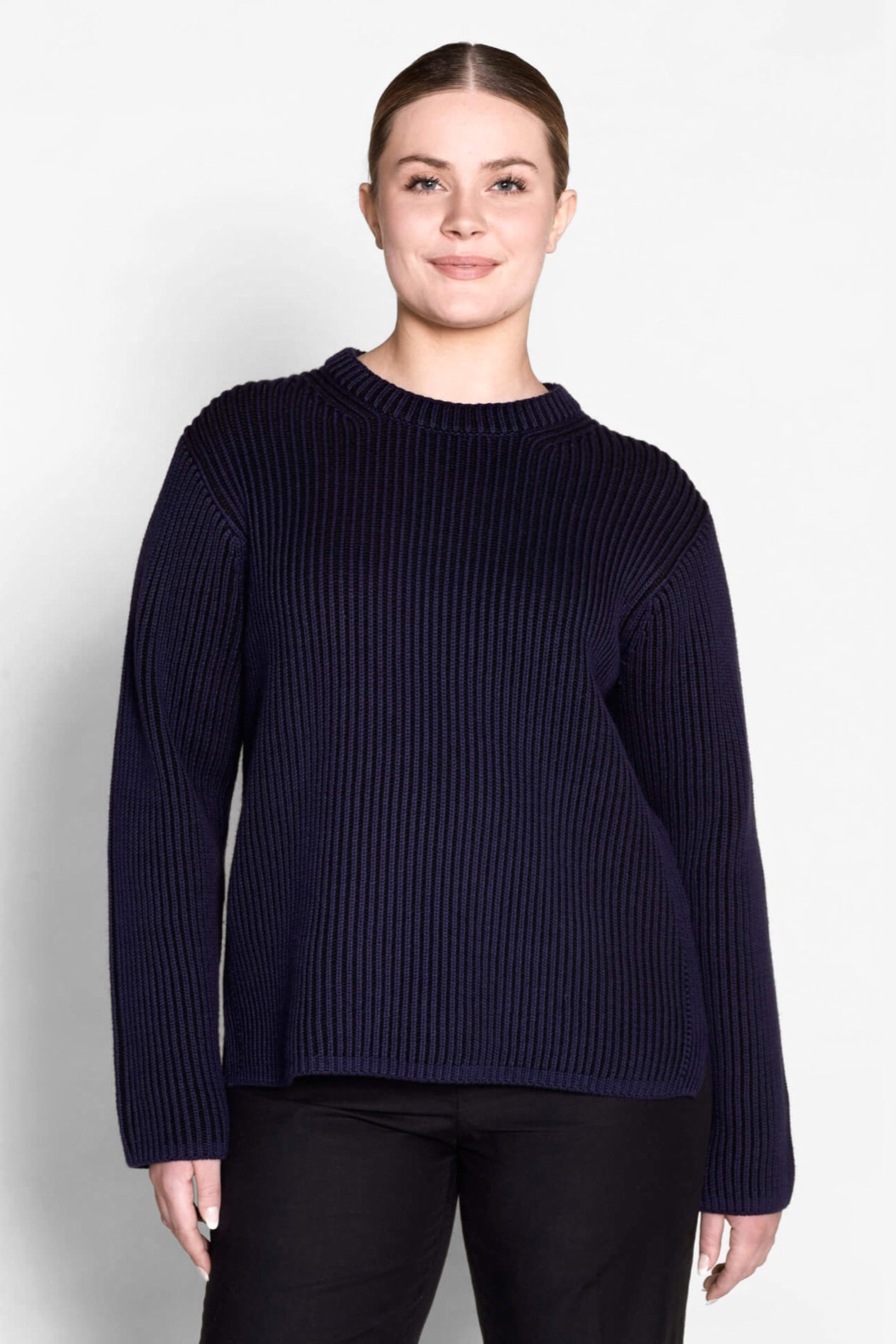 Model sports a Cyme Copenhagen navy ribbed sweater, demonstrating the classic fit and sustainable materials that are hallmarks of this fashion-forward Scandinavian brand, catering to all women.
