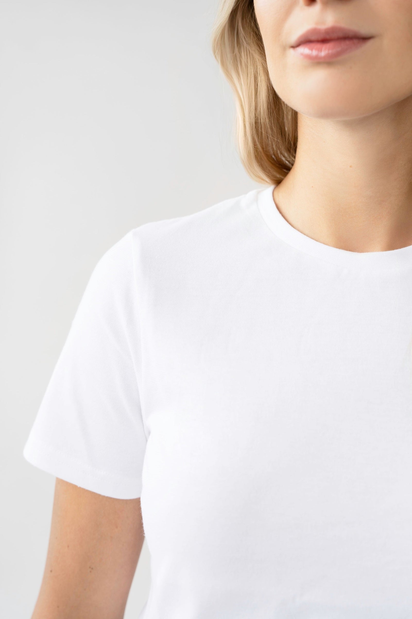 Person wearing a plain white t-shirt against a light gray background