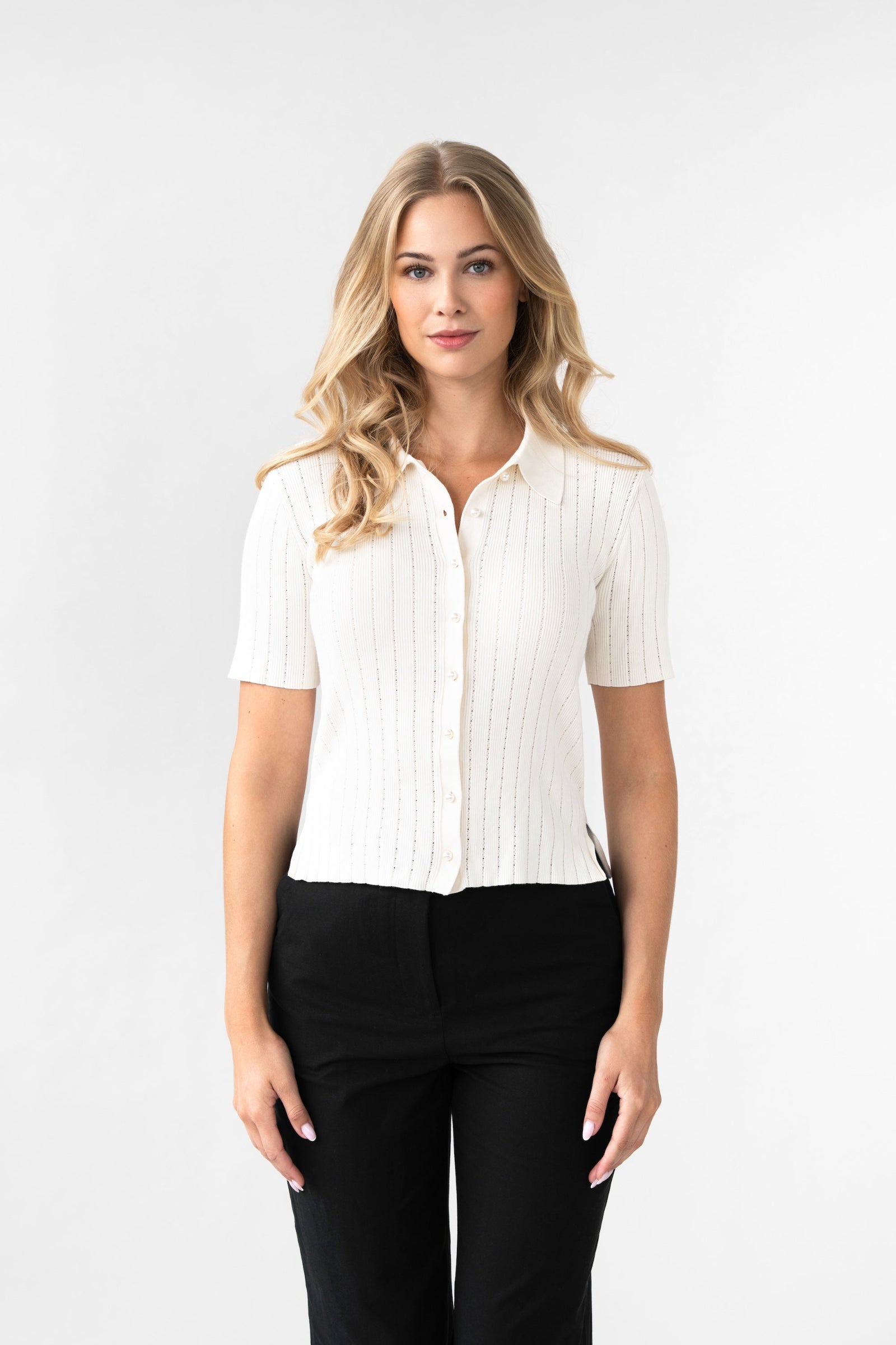 Woman wearing a white blouse and black pants on a white background