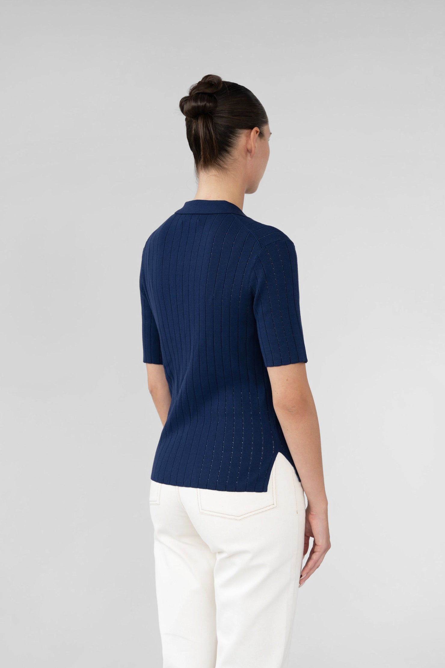 Person wearing a navy blue shirt and white pants on a light gray background