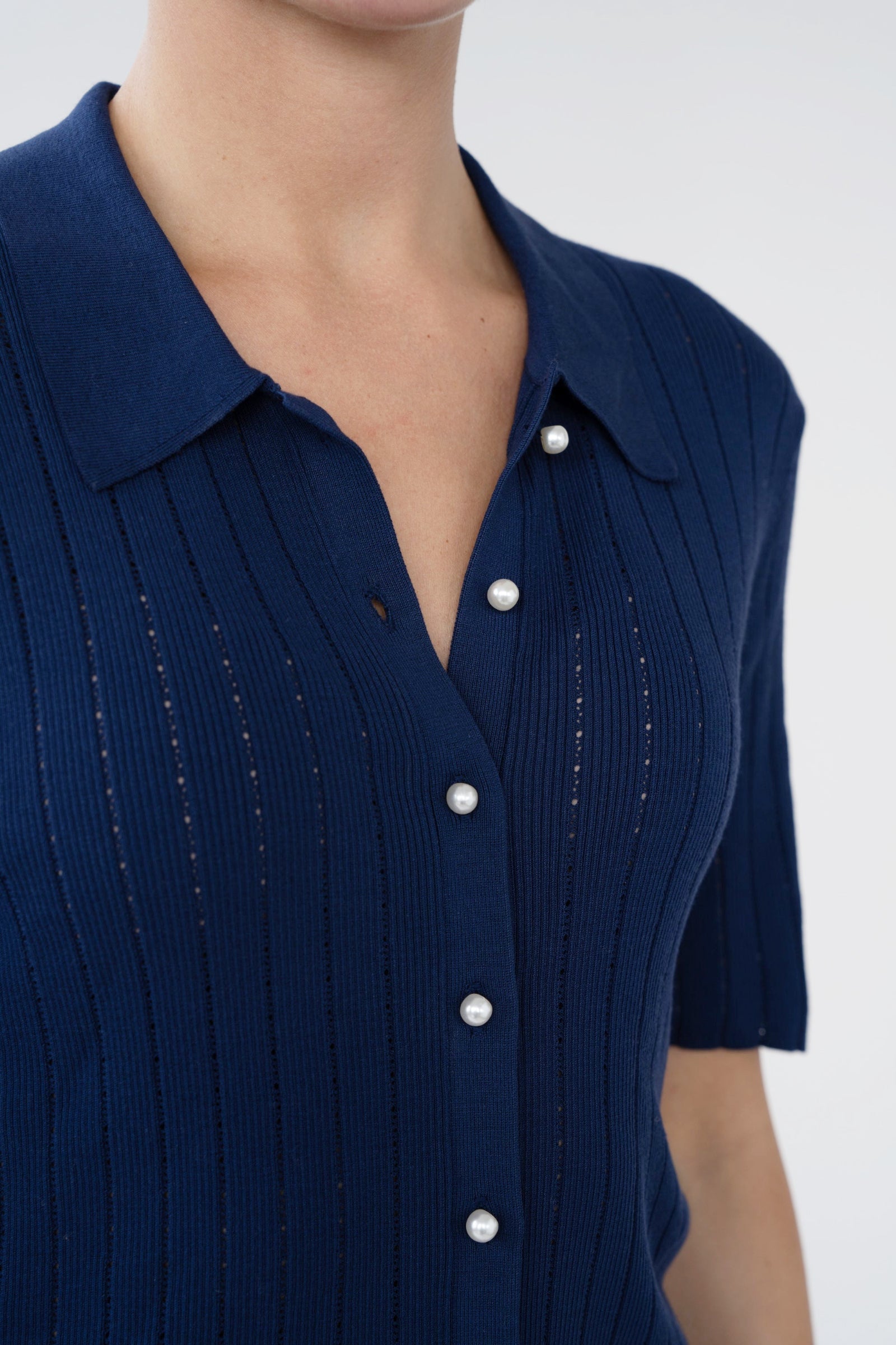 Navy blue dress with white buttons on a plain background