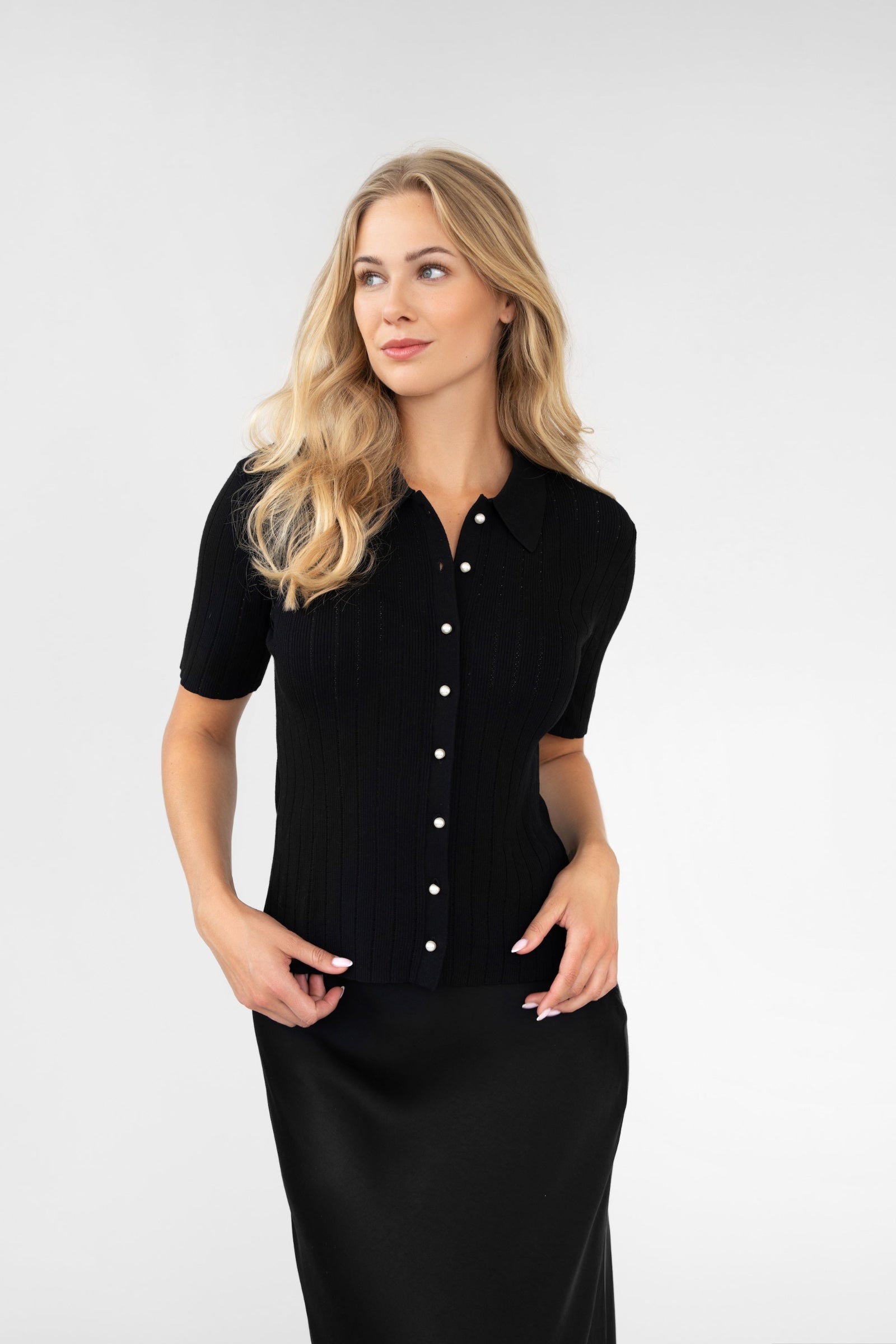 Woman wearing a black short-sleeve button-up shirt against a white background