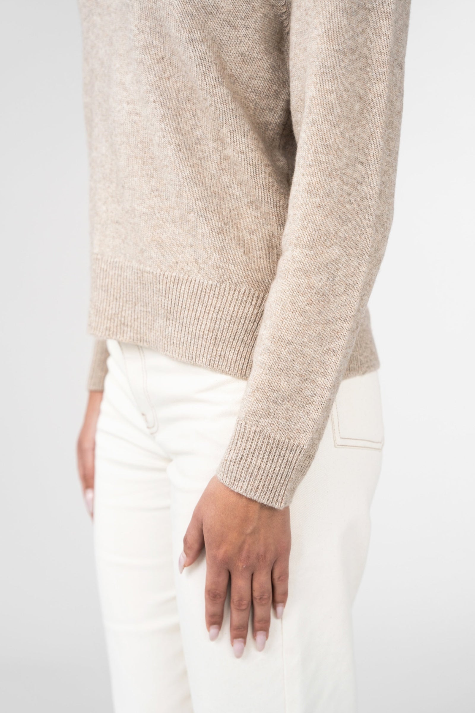 Beige sweater worn by a person on a white background