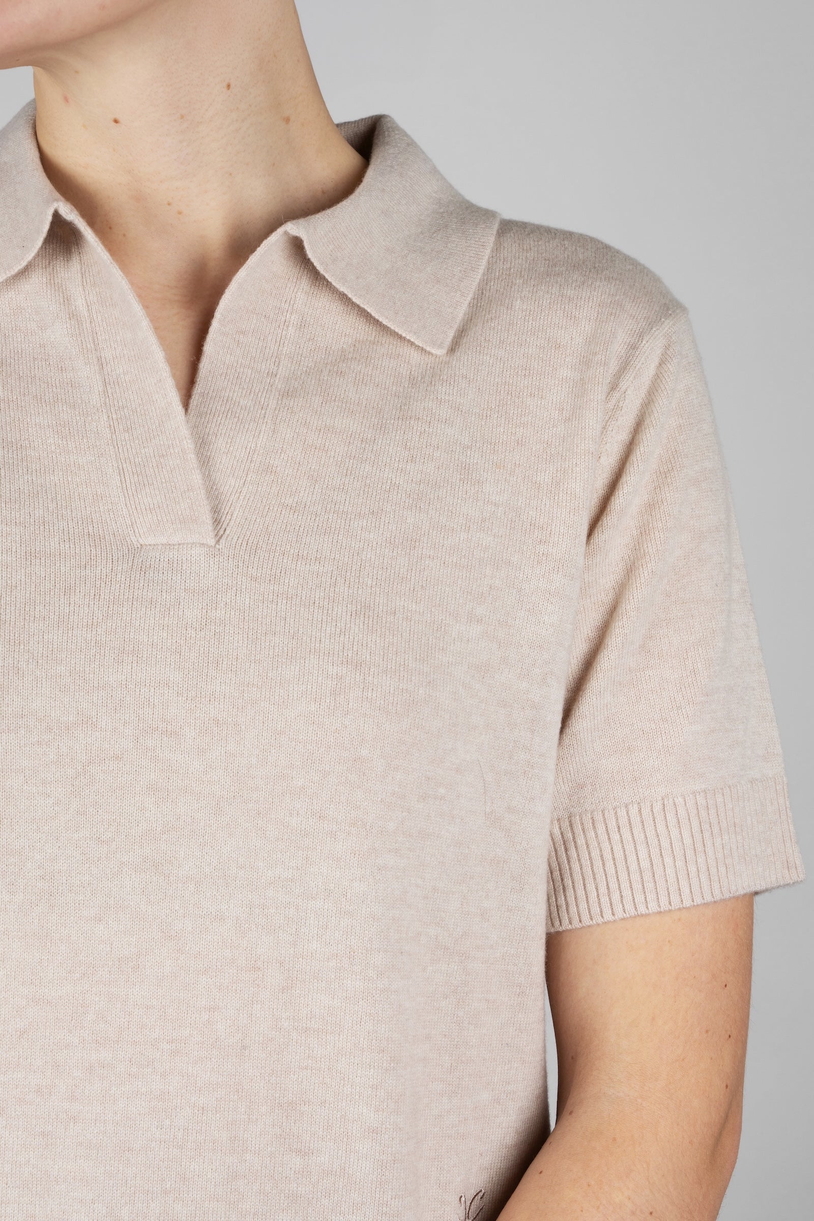 Beige short-sleeve shirt worn by a person on a plain background