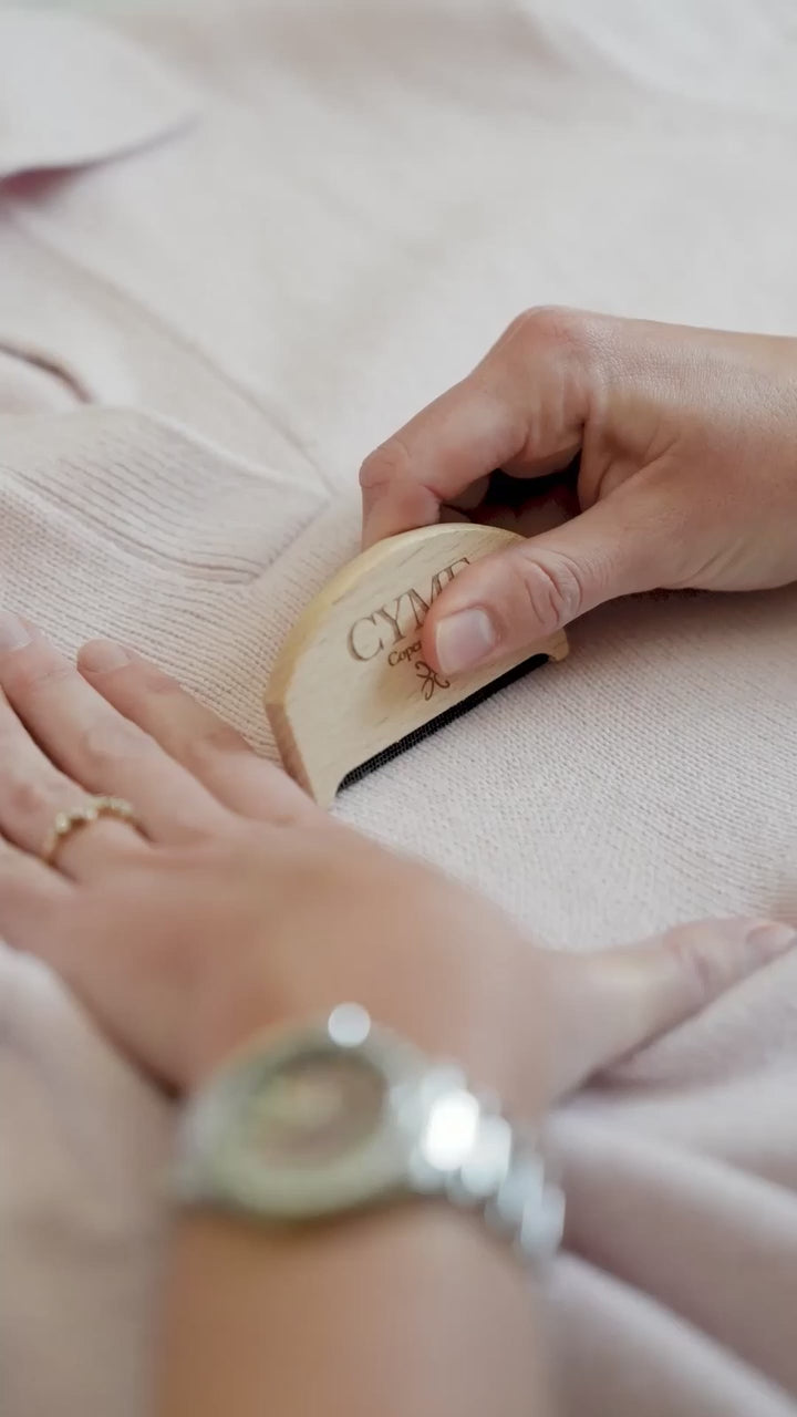 Woman using a CYME Copenhagen wool comb to remove pilling of our beautiful cashmere polo jumper