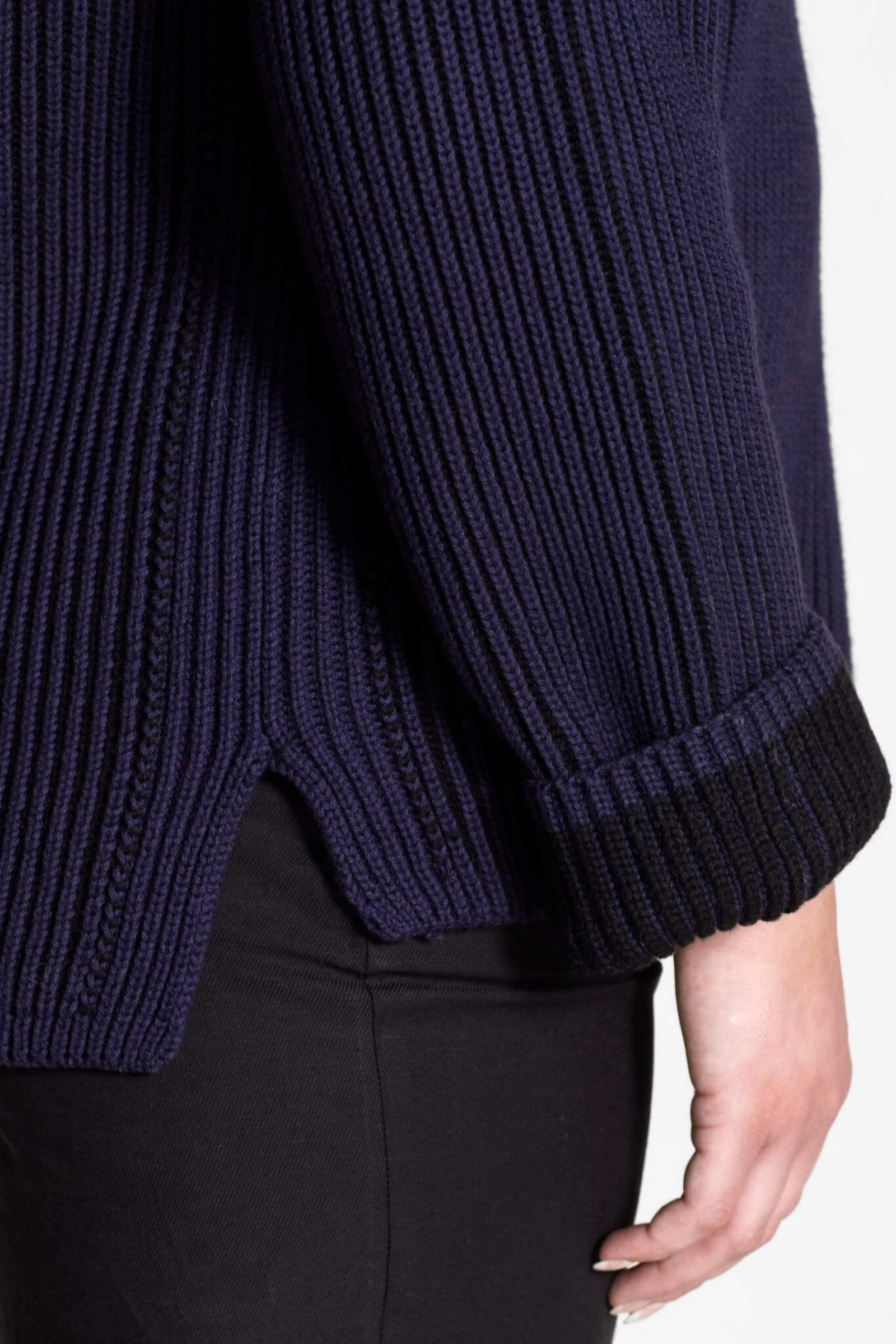 Detail of the side view of Cyme Copenhagen's navy ribbed sweater, featuring a high-low hem and textured knit, aligning with Scandinavian fashion trends and the brand's dedication to sustainable materials in women's clothing.