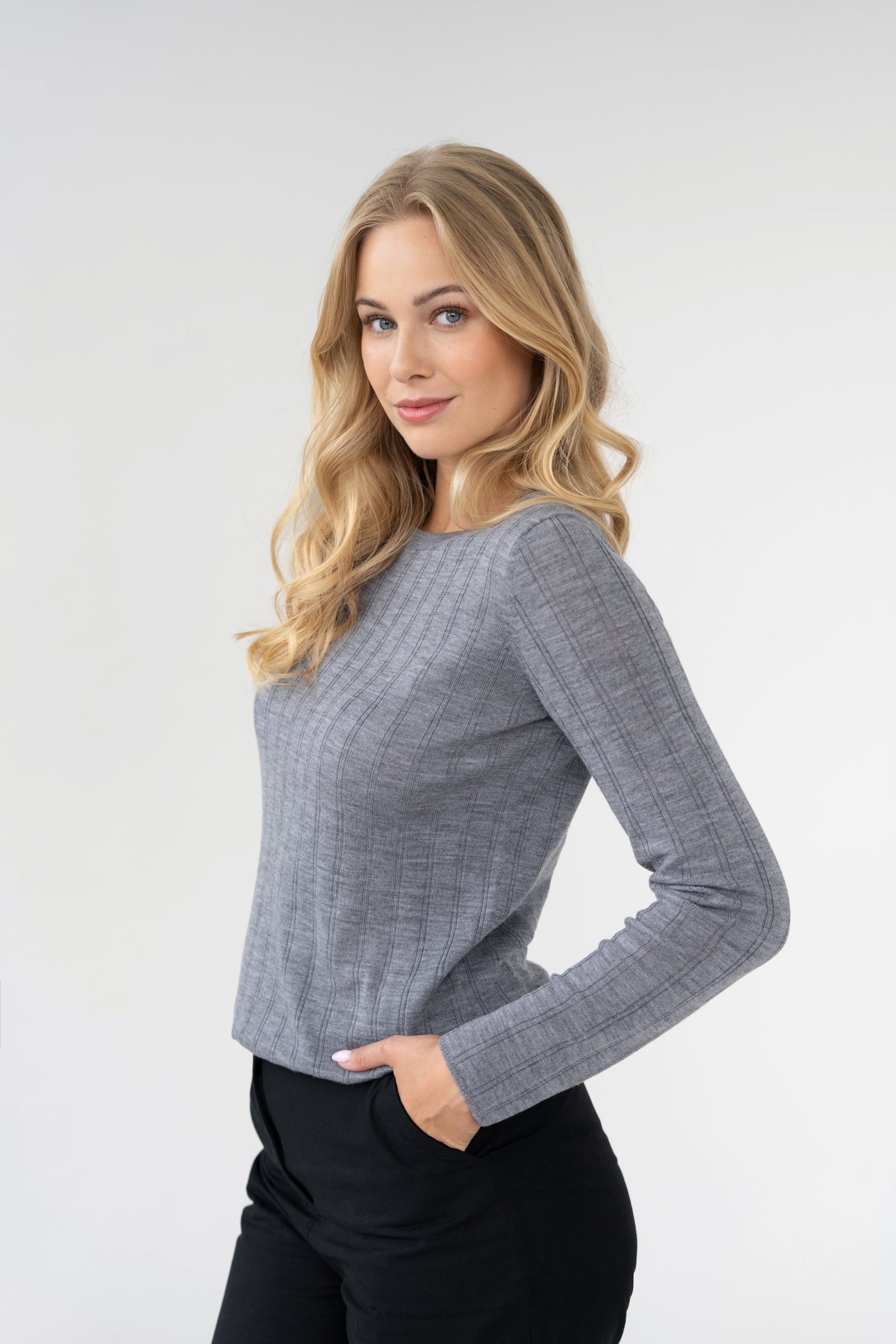 On-model three-quarter view of ribbed crew-neck sweater, grey, long sleeve, studio.
