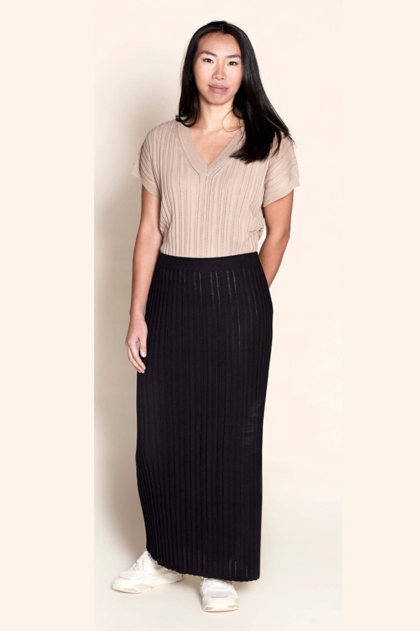 Model wearing a Cyme Copenhagen ribbed knit set featuring a taupe short-sleeved top and a contrasting black skirt, merging Danish design with sustainable fashion in a sophisticated women's clothing ensemble.