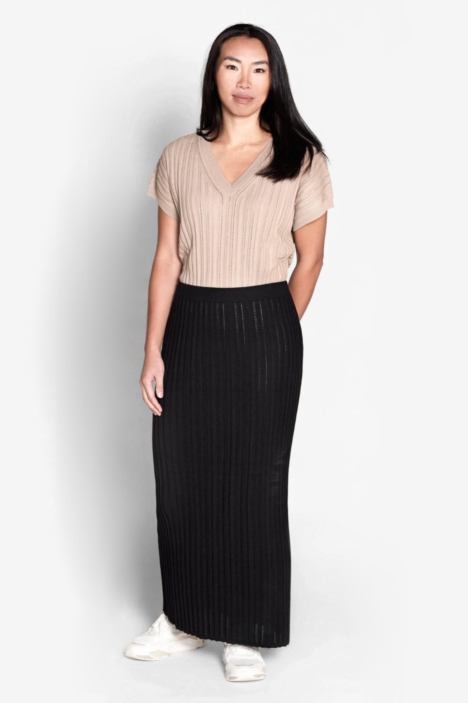 Model wearing a Cyme Copenhagen ribbed knit set featuring a taupe short-sleeved top and a contrasting black skirt, merging Danish design with sustainable fashion in a sophisticated women's clothing ensemble.