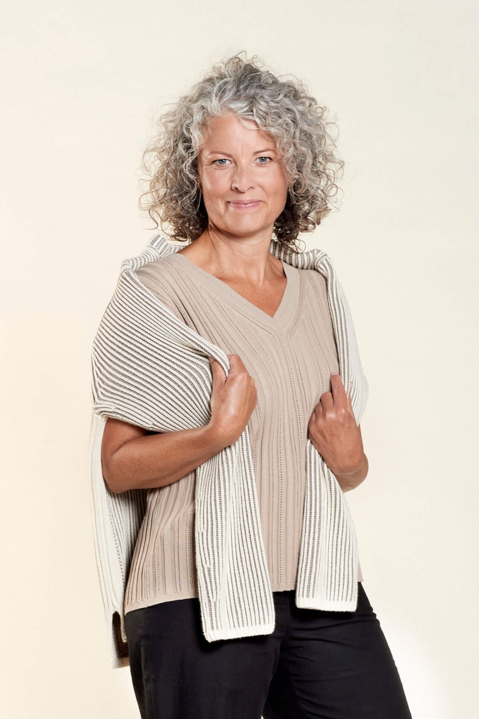 Model wears Cyme Copenhagen's coordinated taupe knit top and skirt set, showcasing the Danish brand's commitment to sustainable materials and elegant design in women's fashion, available from top fashion stores in Denmark.